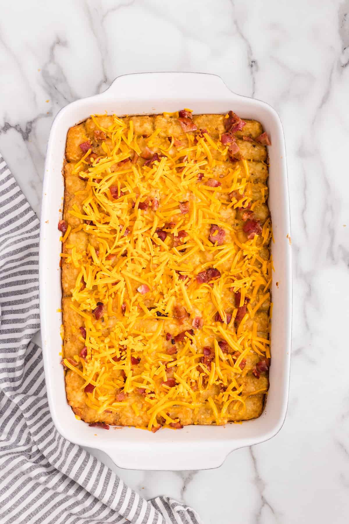 Overhead picture with cheese spread over casserole ingredients in white pan