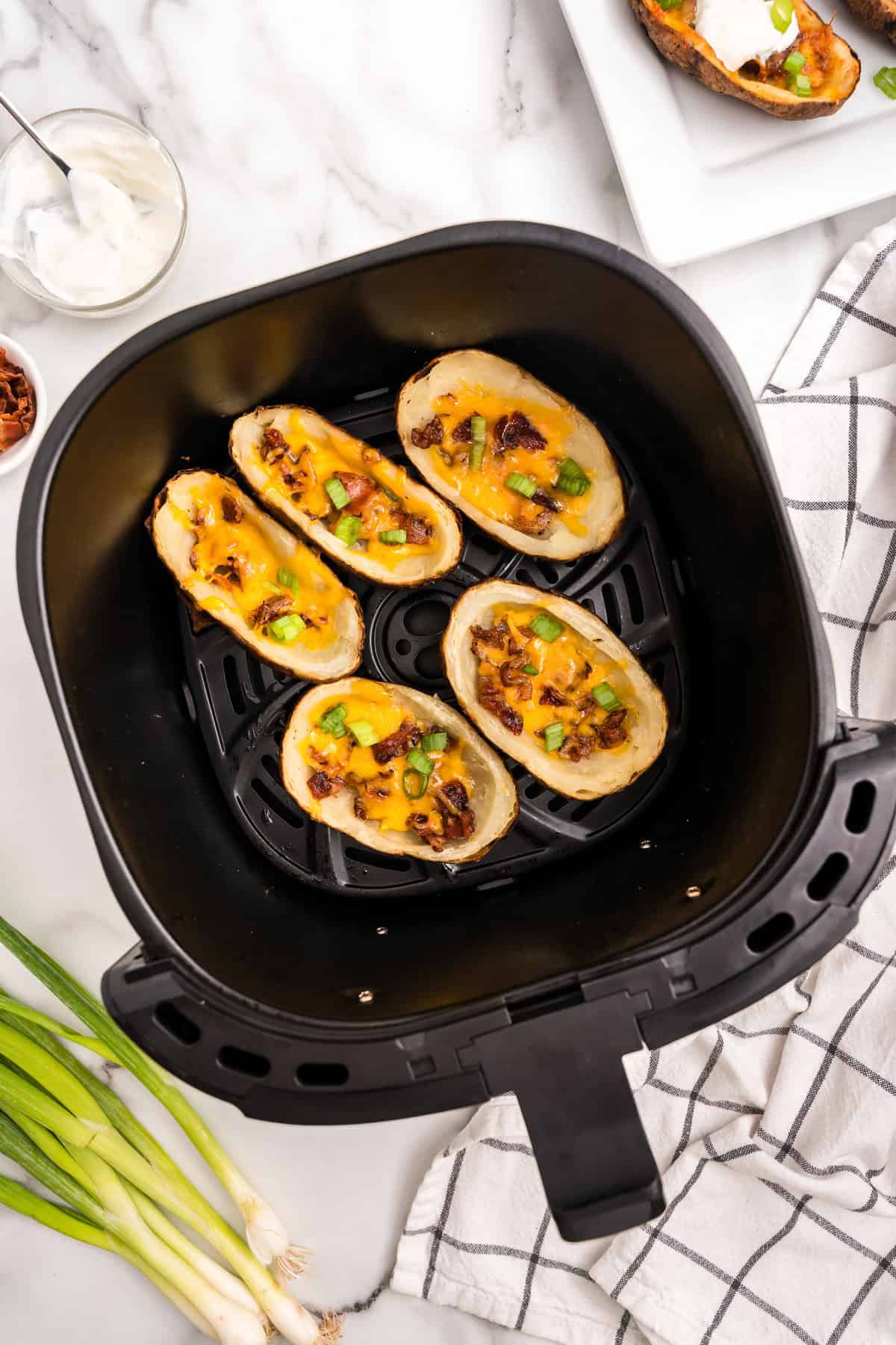Adding chopped green onions to Air Fryer Potato Skins in air fryer