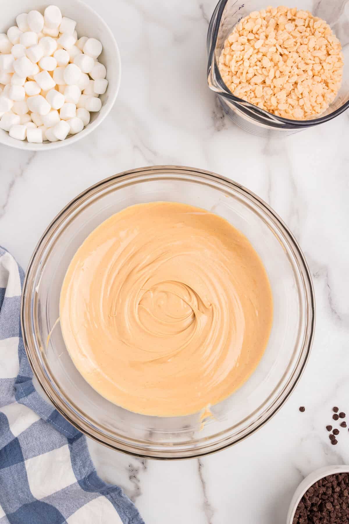 Blended white chocolate and peanut butter mixture in glass mixing bowl for Avalanche Cookies recipe