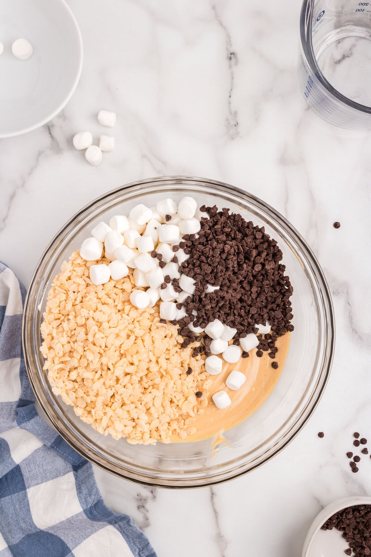 Adding mini chocolate chips and marshmallows, and rice crispy cereal to mixture in bowl for Avalanche Cookies recipe