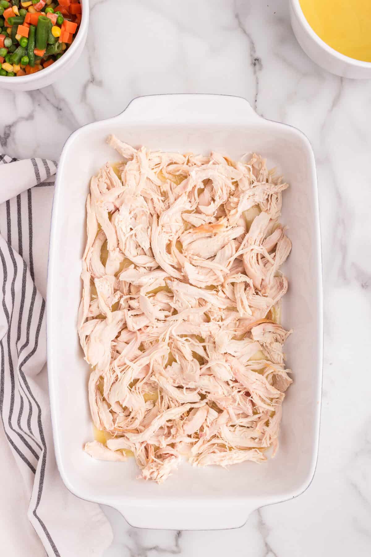Overhead picture of white baking dish with shredded chicken in it.