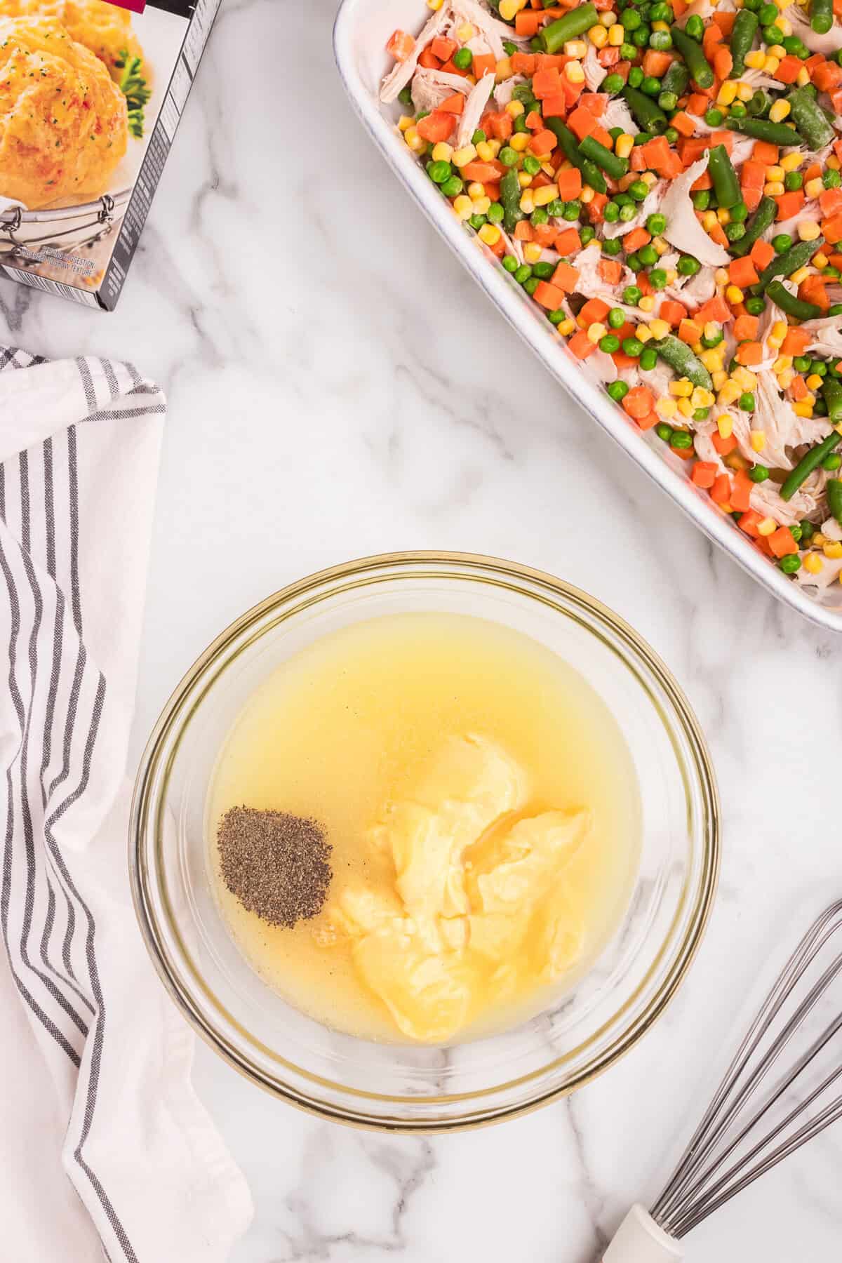 Overhead picture of glass bowl with chicken cobbler filling ingredients.