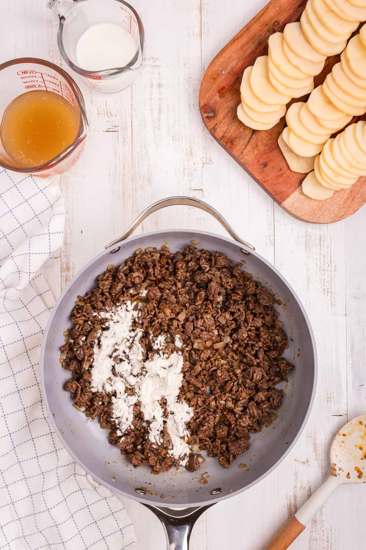 Overhead picture of metal pot with cooked ground beef and seasonings in it.