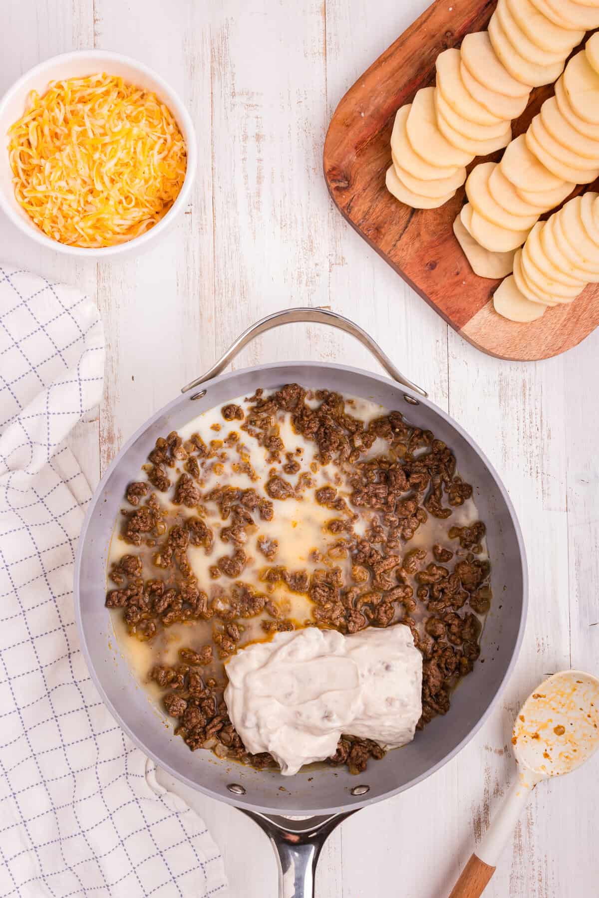Overhead picture of metal pot with ground beef and potato casserole ingredients in it.