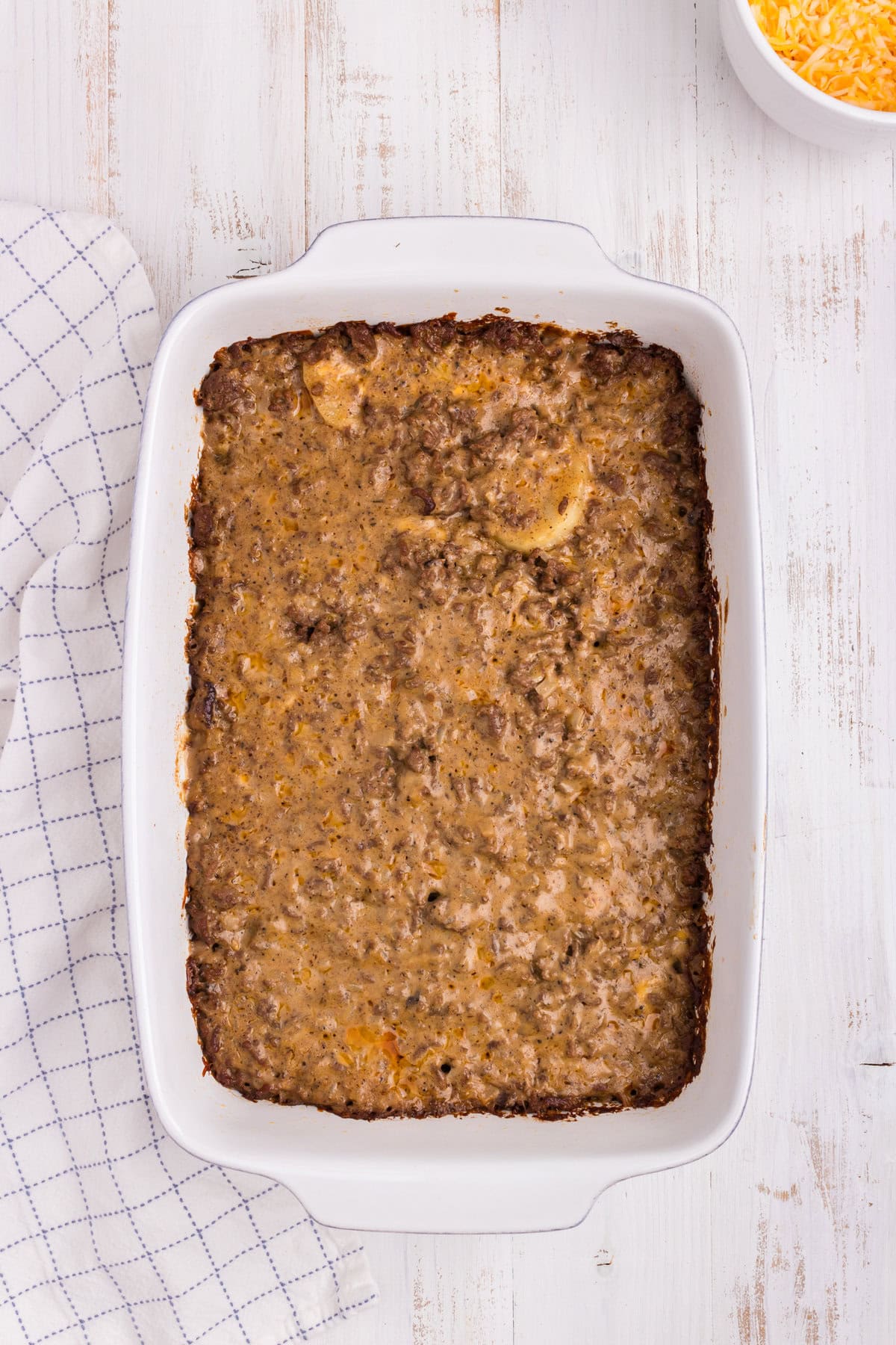 Overhead picture of white pan with ground beef and potato ingredients cooked in it.