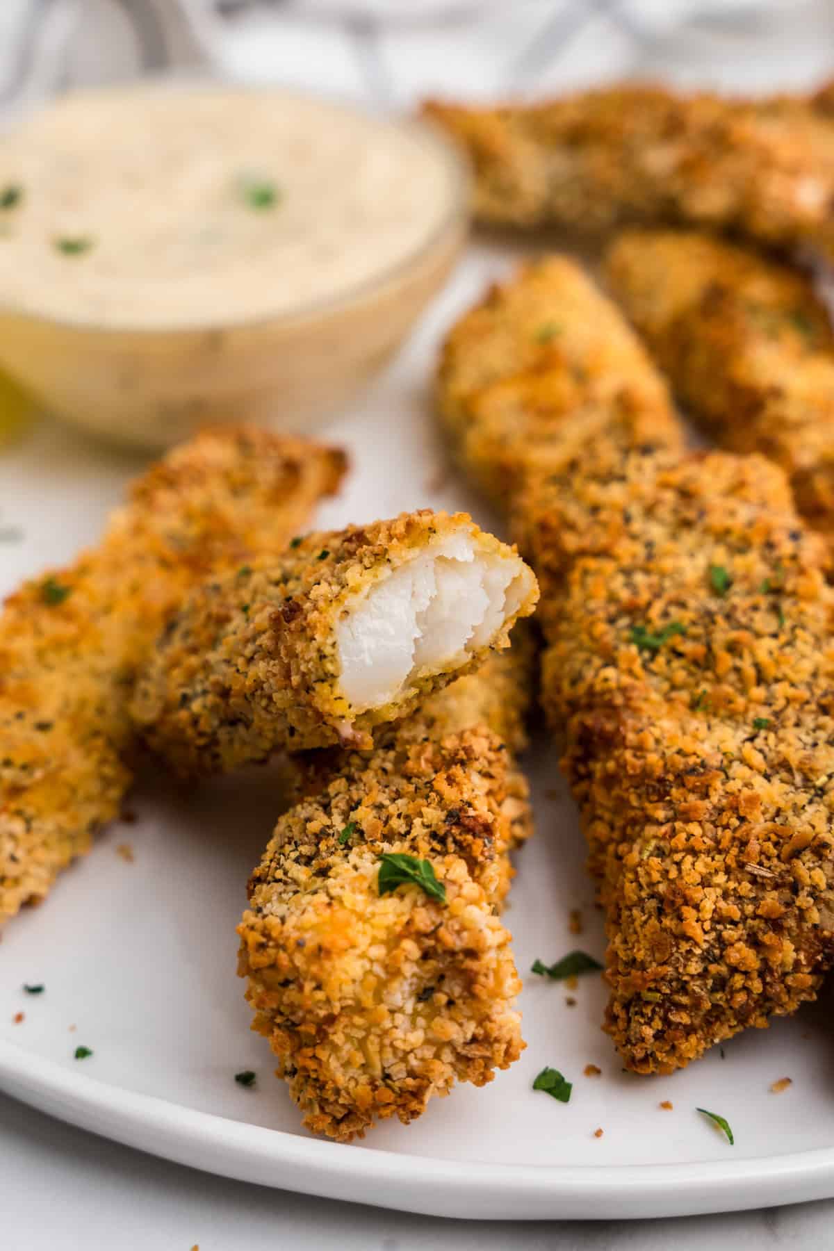 Close up image of air fryer fish sticks with a bite taken out of one.