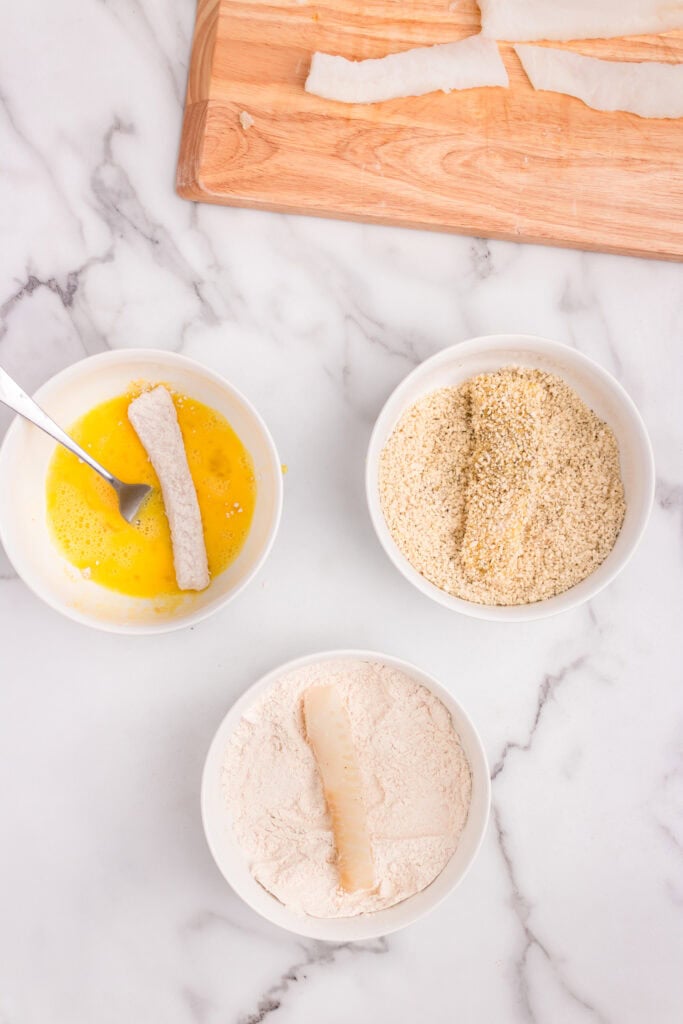 Overhead picture with three bowls and a wooden cutting board each with an ingredient in them.