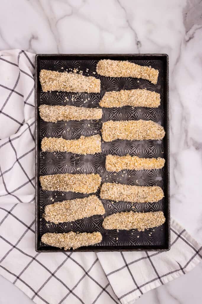 Overhead picture of baking sheet with uncooked air fryer fish sticks on it.