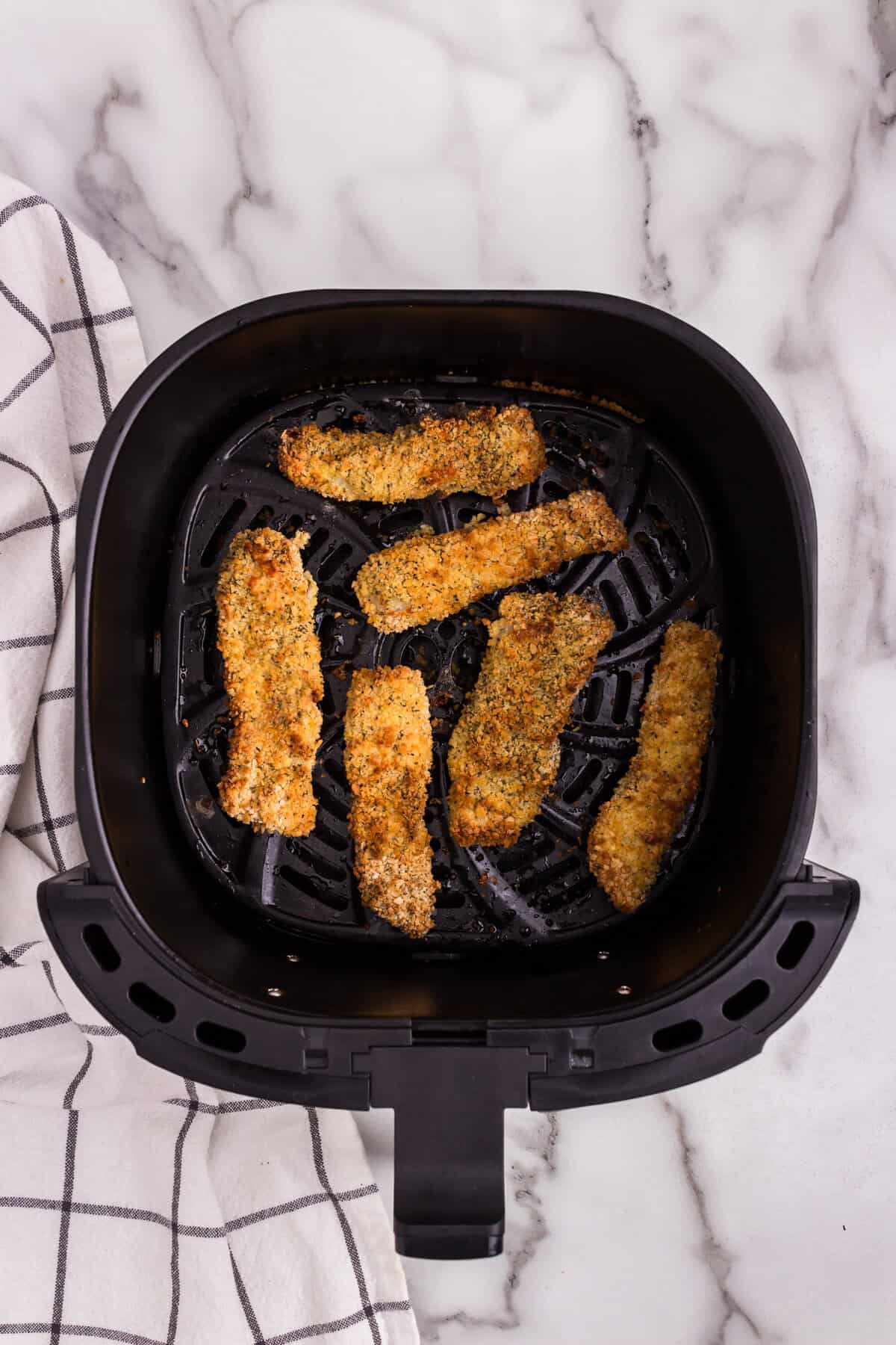 Overhead picture of air fryer basket with cooked fish sticks in it.