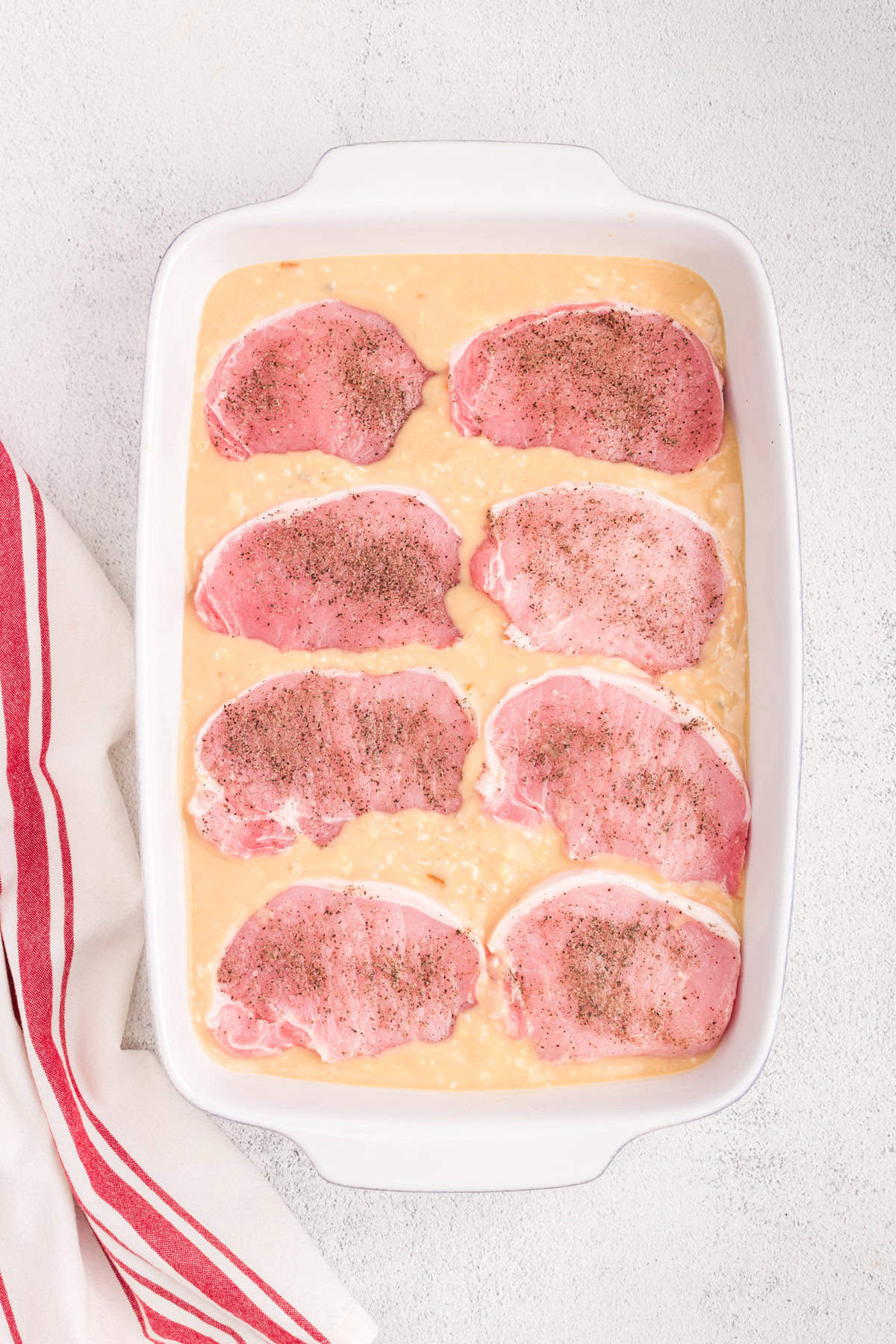 Adding 8 salt and peppered pork chops into mixture for Baked Pork Chops and Rice recipe