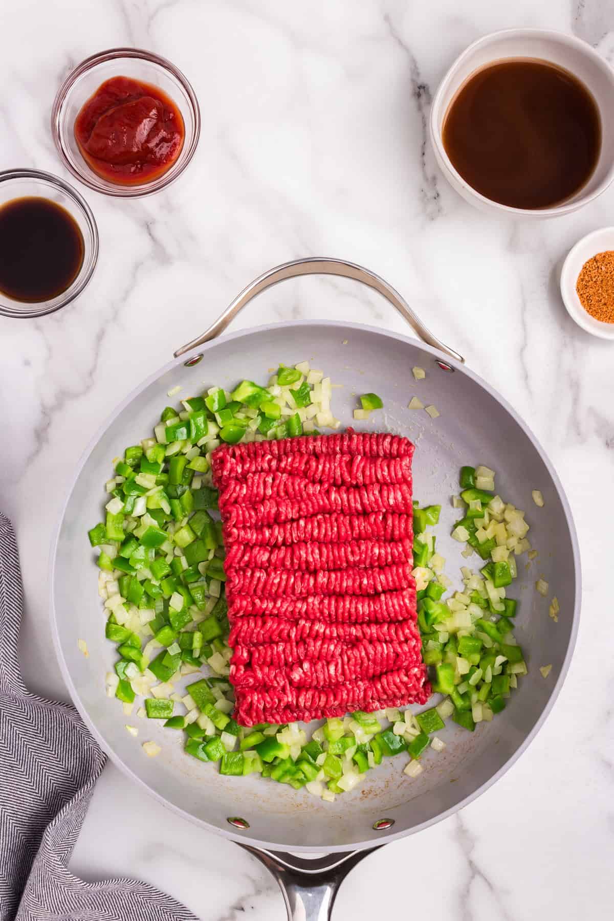 Overhead picture of raw Philly Cheesesteak Sloppy Joe ingredients in a frying pan.