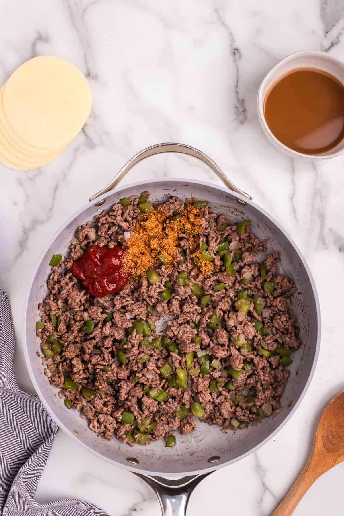 Overhead picture of cooked Cheesesteak Sloppy Joe ingredients unmixed in a pan.
