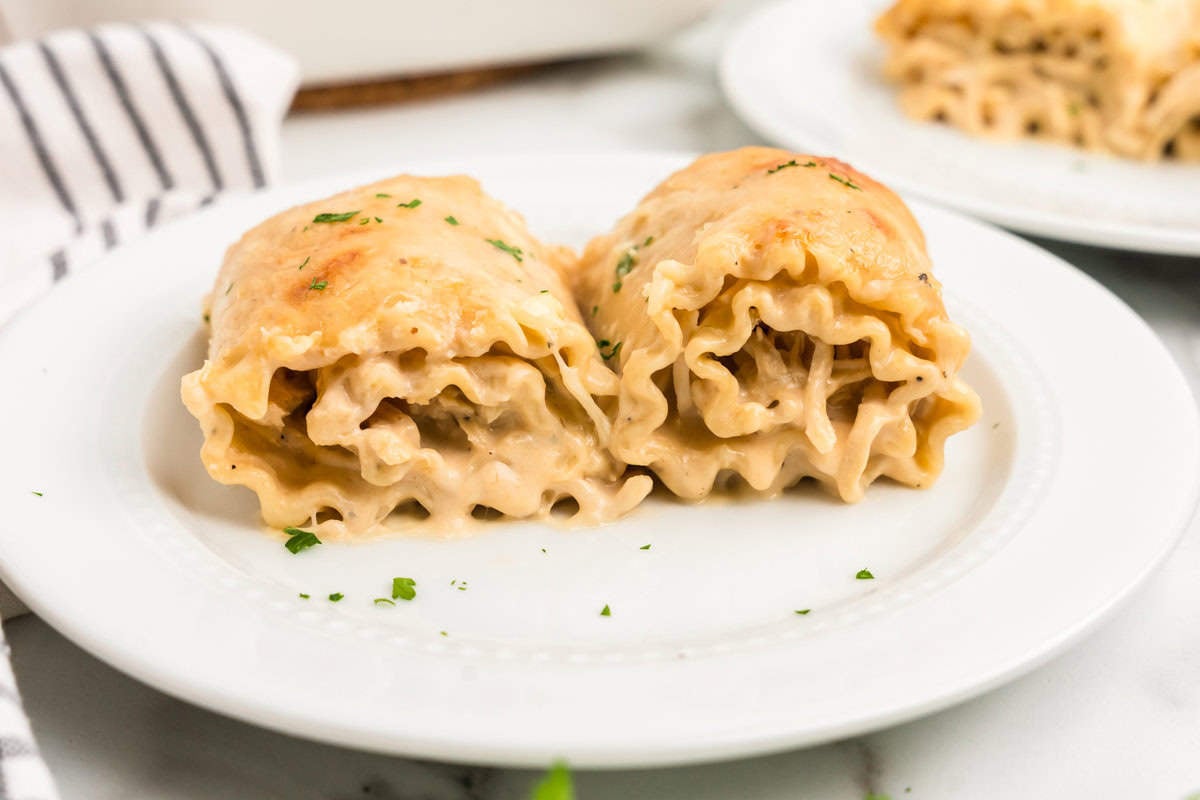 White Plate with two Chicken Alfredo Roll Ups on it.