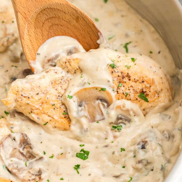 Using a wooden spoon to stir Skillet Cream of Mushroom Chicken in stovetop skillet
