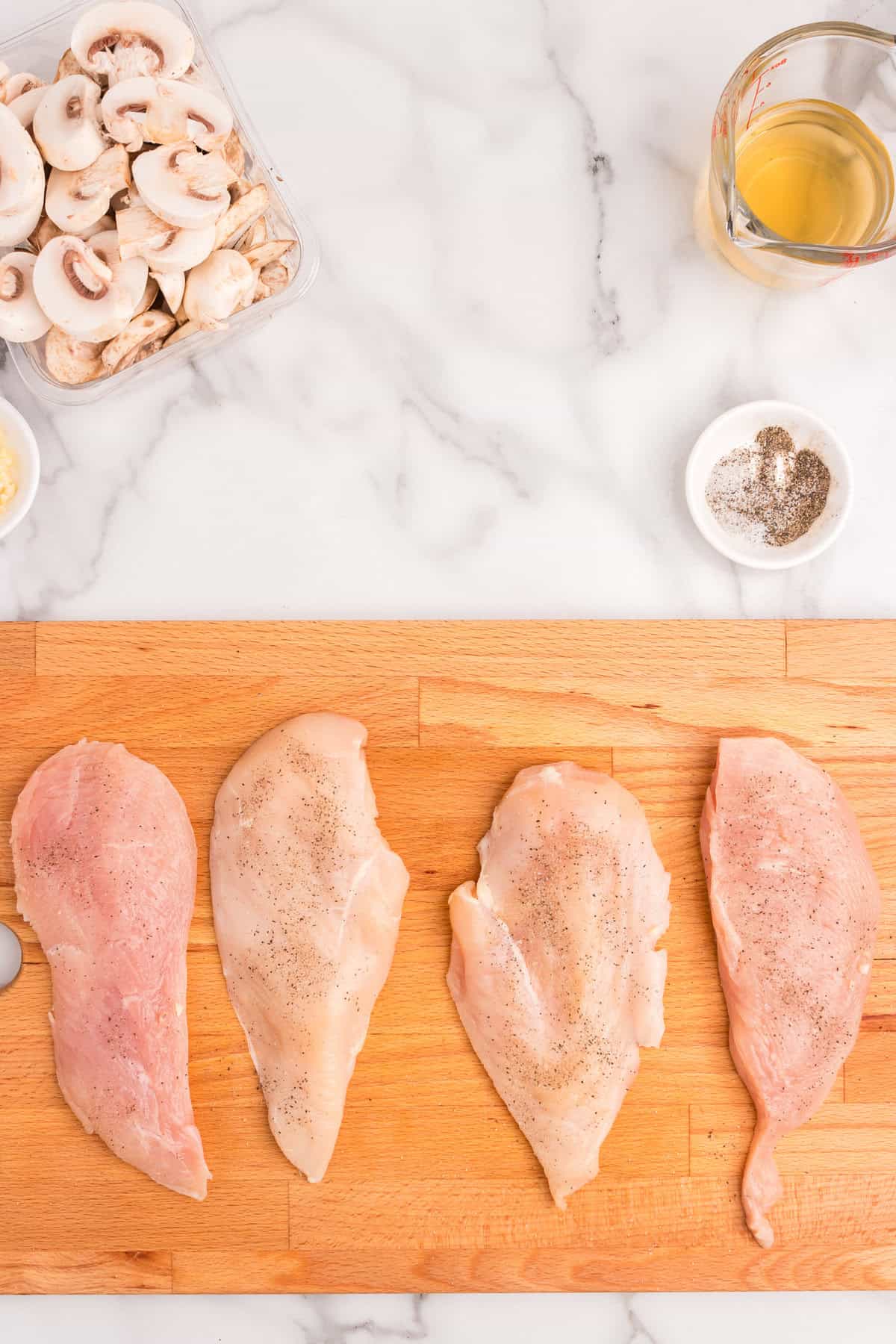 Chicken breasts arranged on wooden cutting board to prepare for Skillet Cream of Mushroom Chicken recipe
