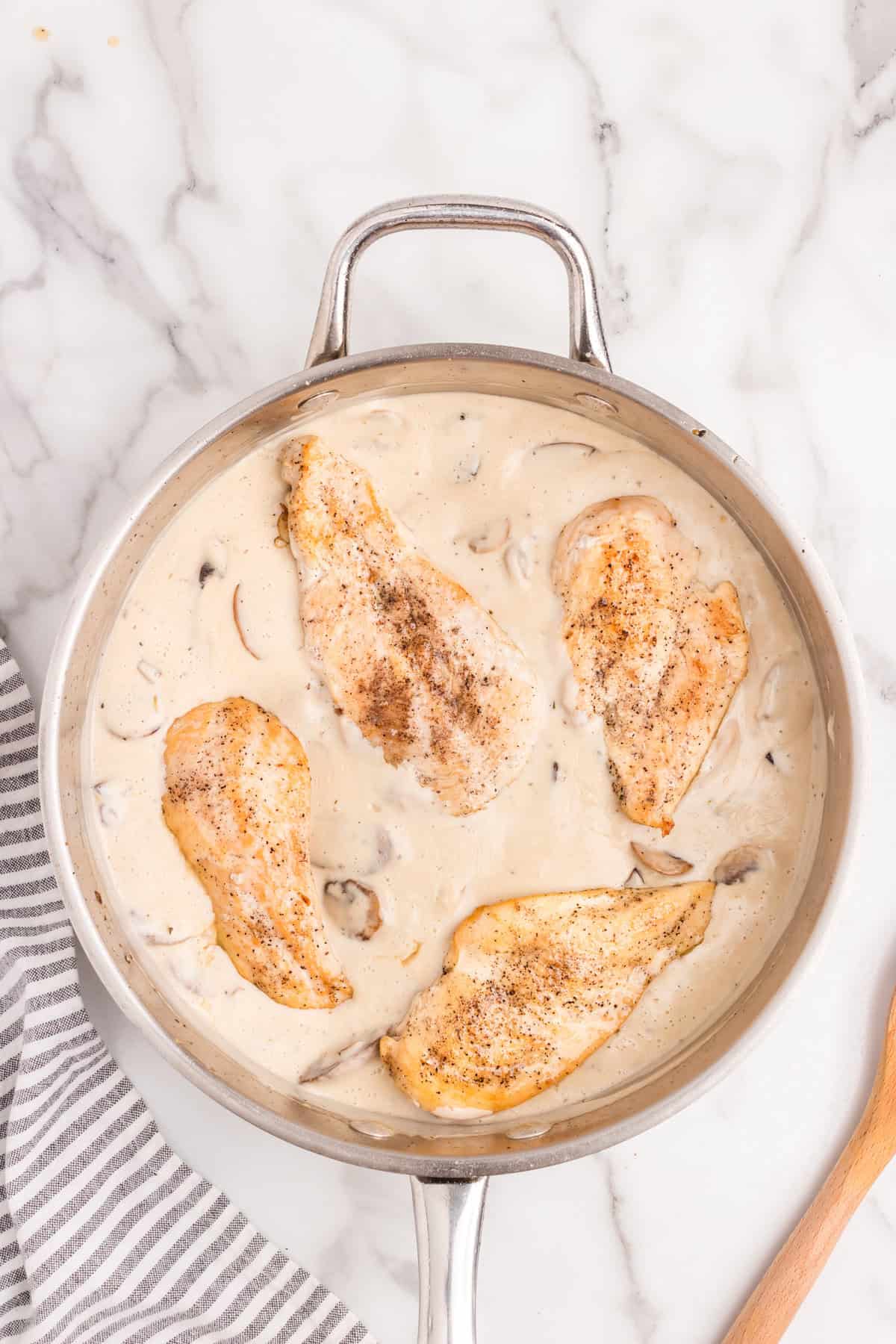 Adding cooked chicken breasts back to skillet ingredients for Skillet Cream of Mushroom Chicken recipe