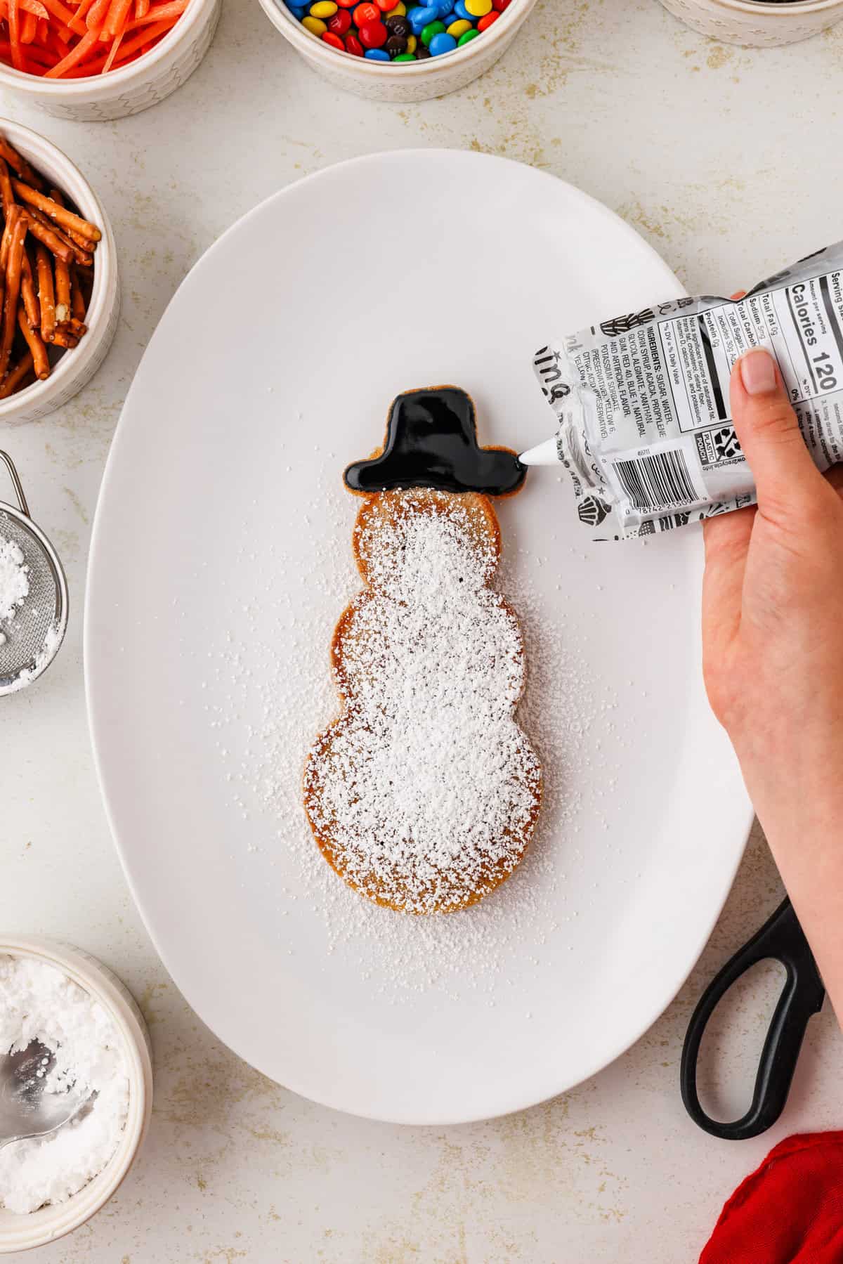 Snowman pancakes hat being frosted on.