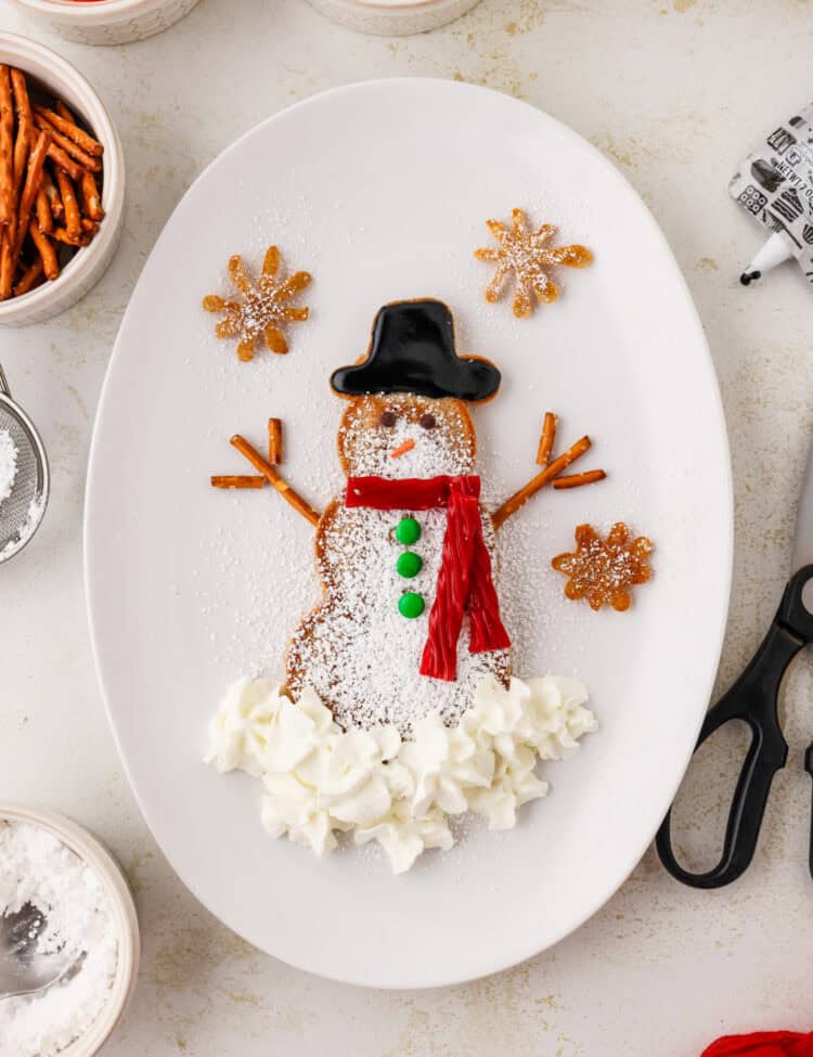 Completed snowman pancake on an white oval plate.