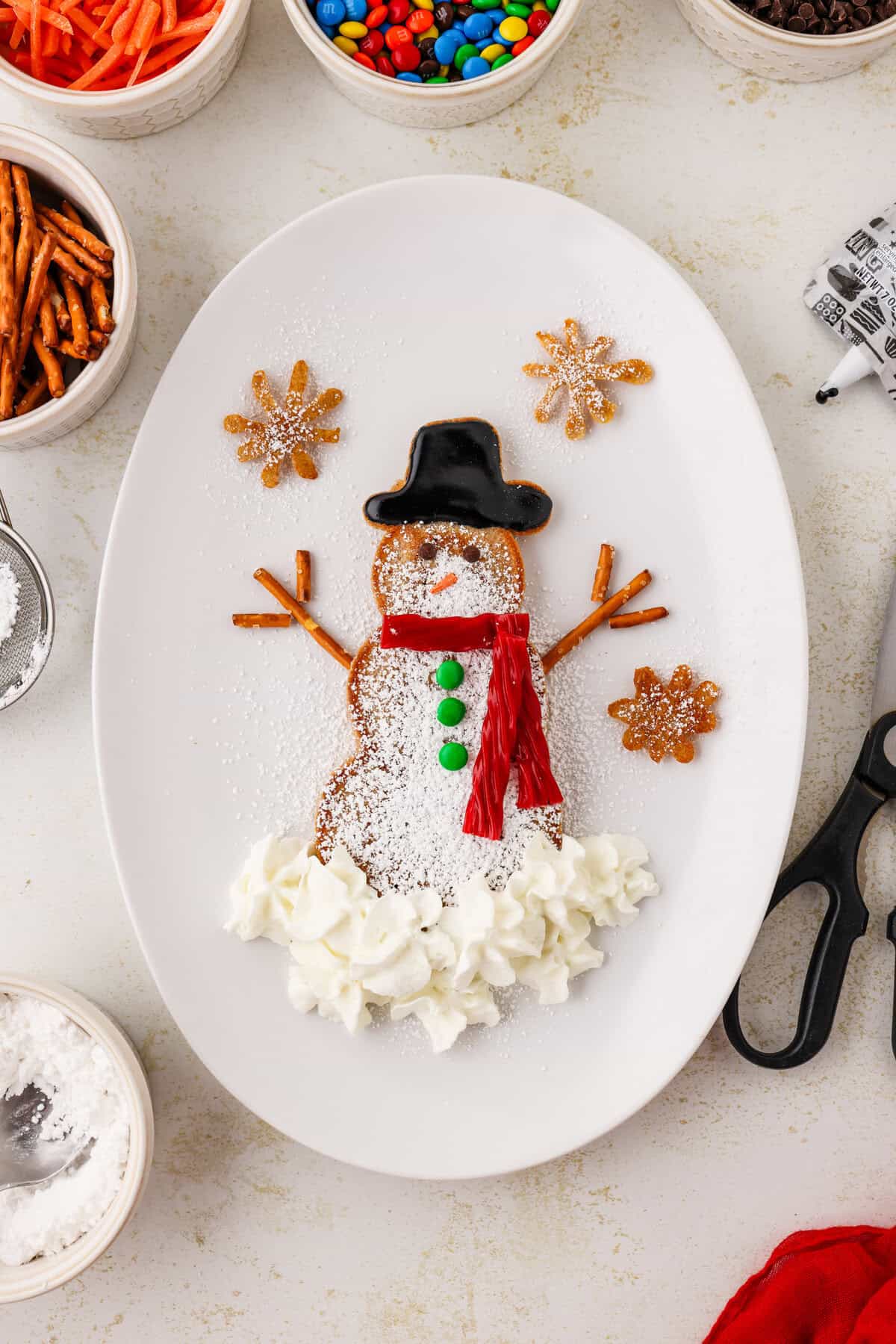 Completed snowman pancake on an white oval plate.