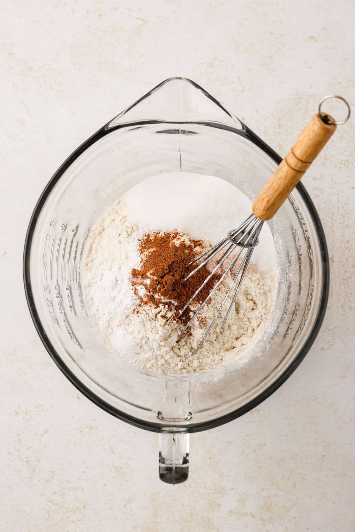 Glass measuring bowl with dry snowman pancake ingredients in it.