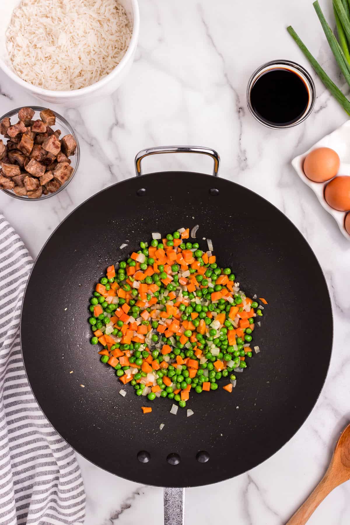 Overhead picture oof peas and carrots in a skillet pan.