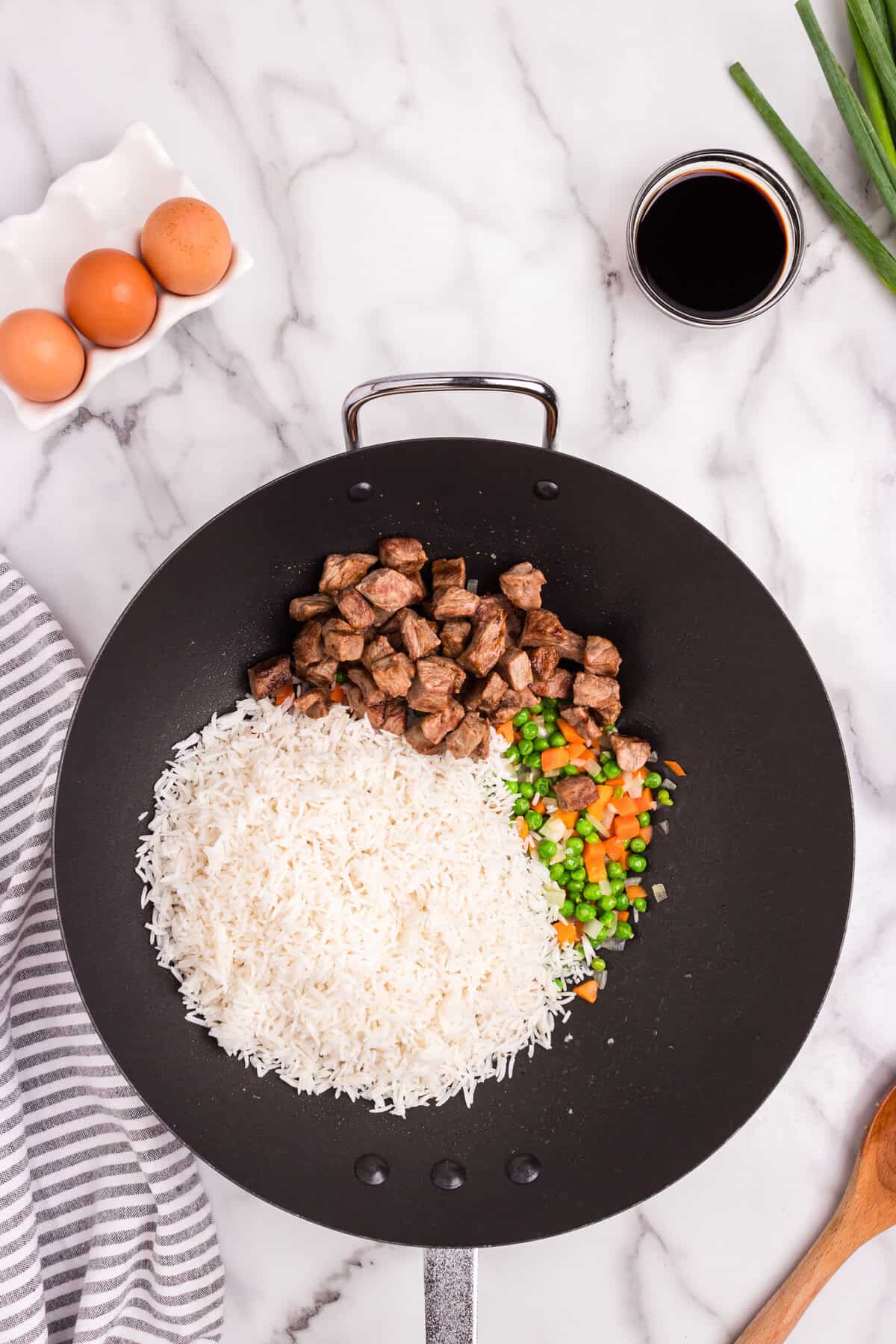 Overhead picture with steak, rice, peas and carrots in it.