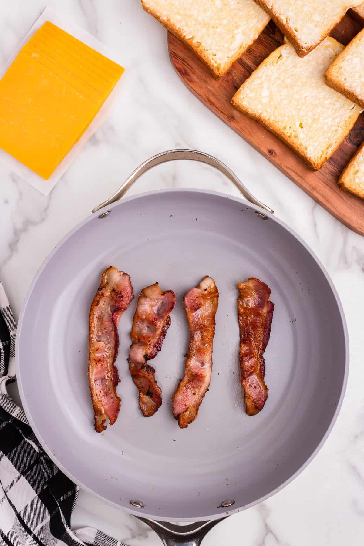 Overhead picture of frying pan with 4 pieces of cooked bacon on it.