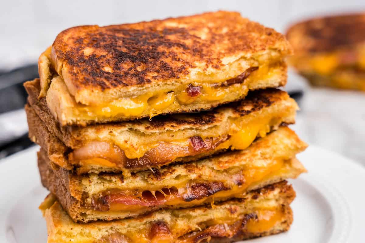 Close up picture of 4 pieces of bacon grilled cheese stacked on top of eachother.