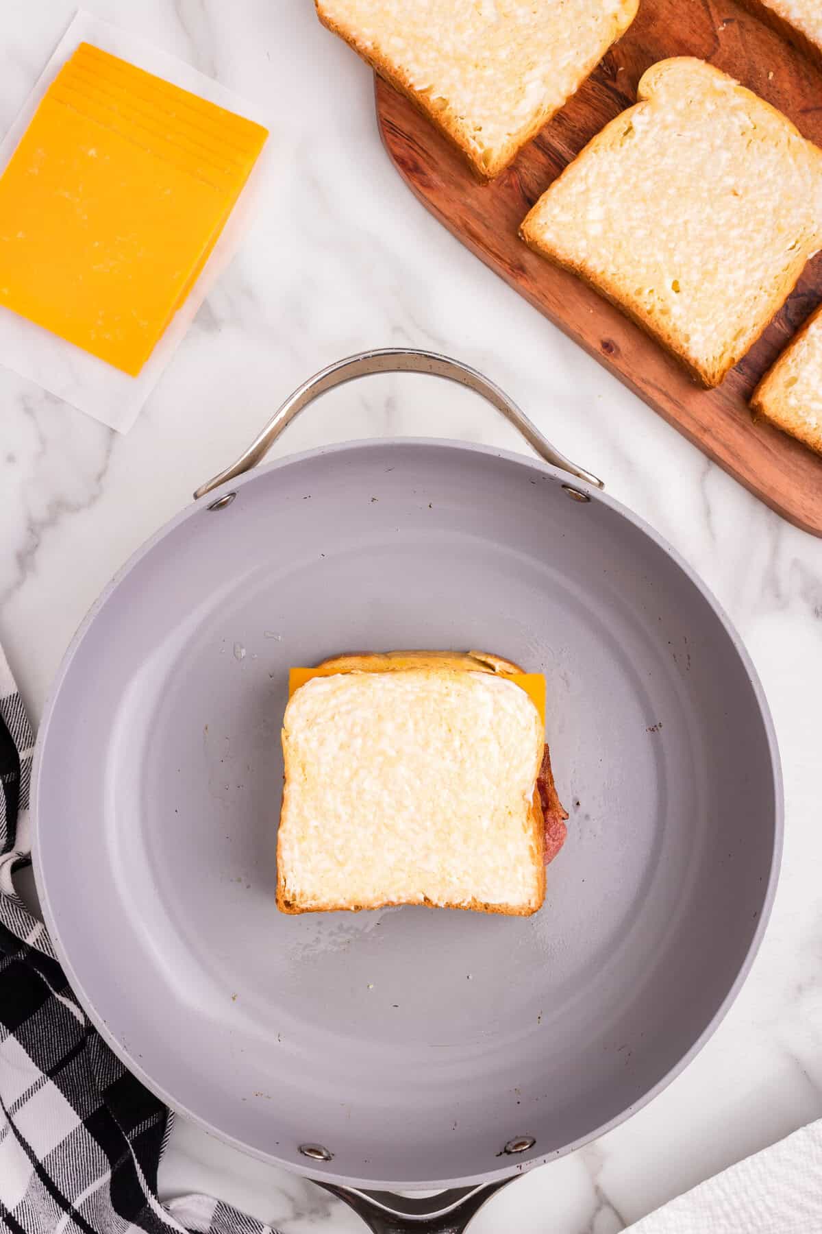 Overhead picture of frying pan with uncooked Bacon Grilled Cheese.