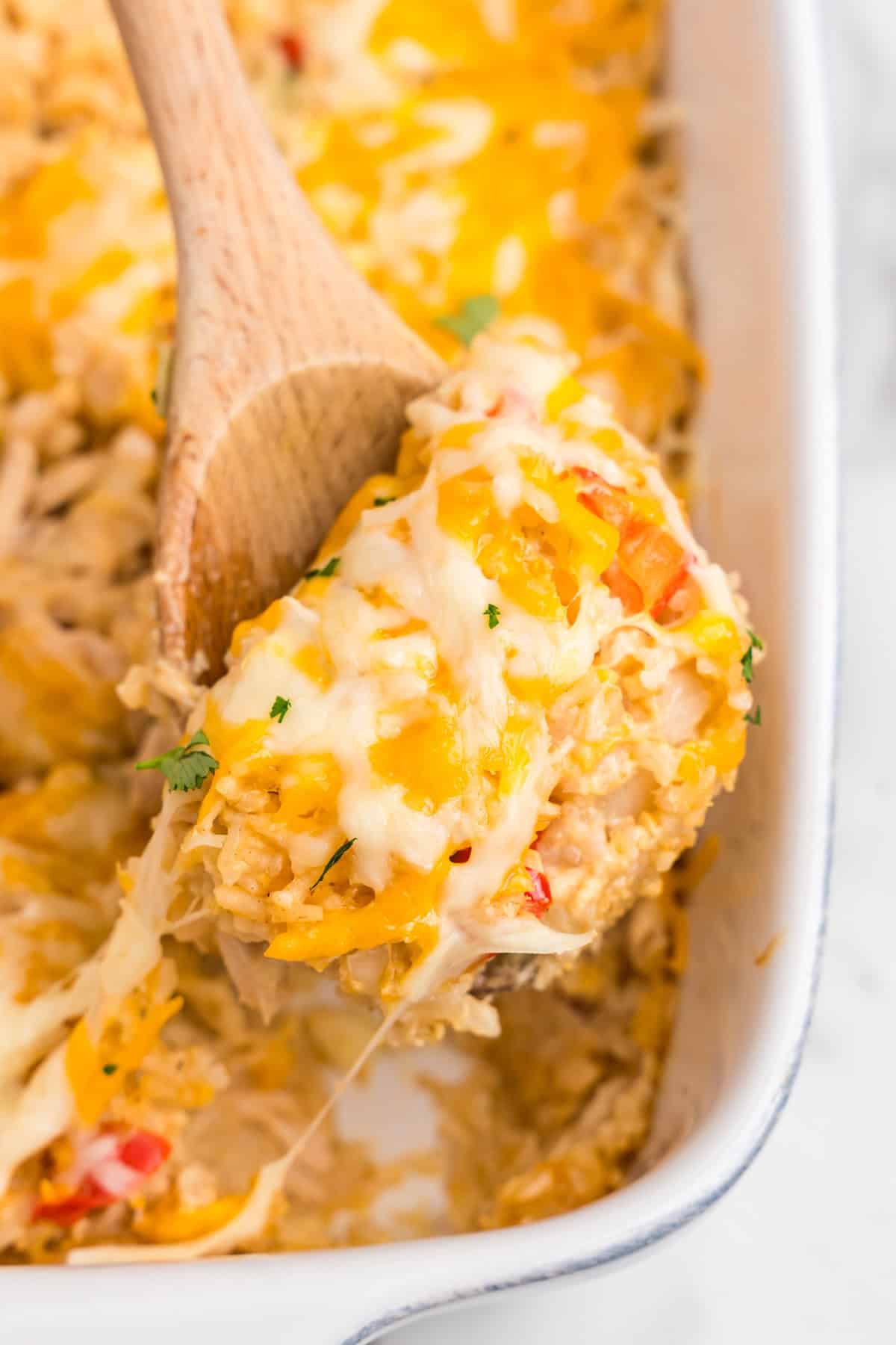 Close up picture of wooden spoon scooping Chicken Fajita Casserole.