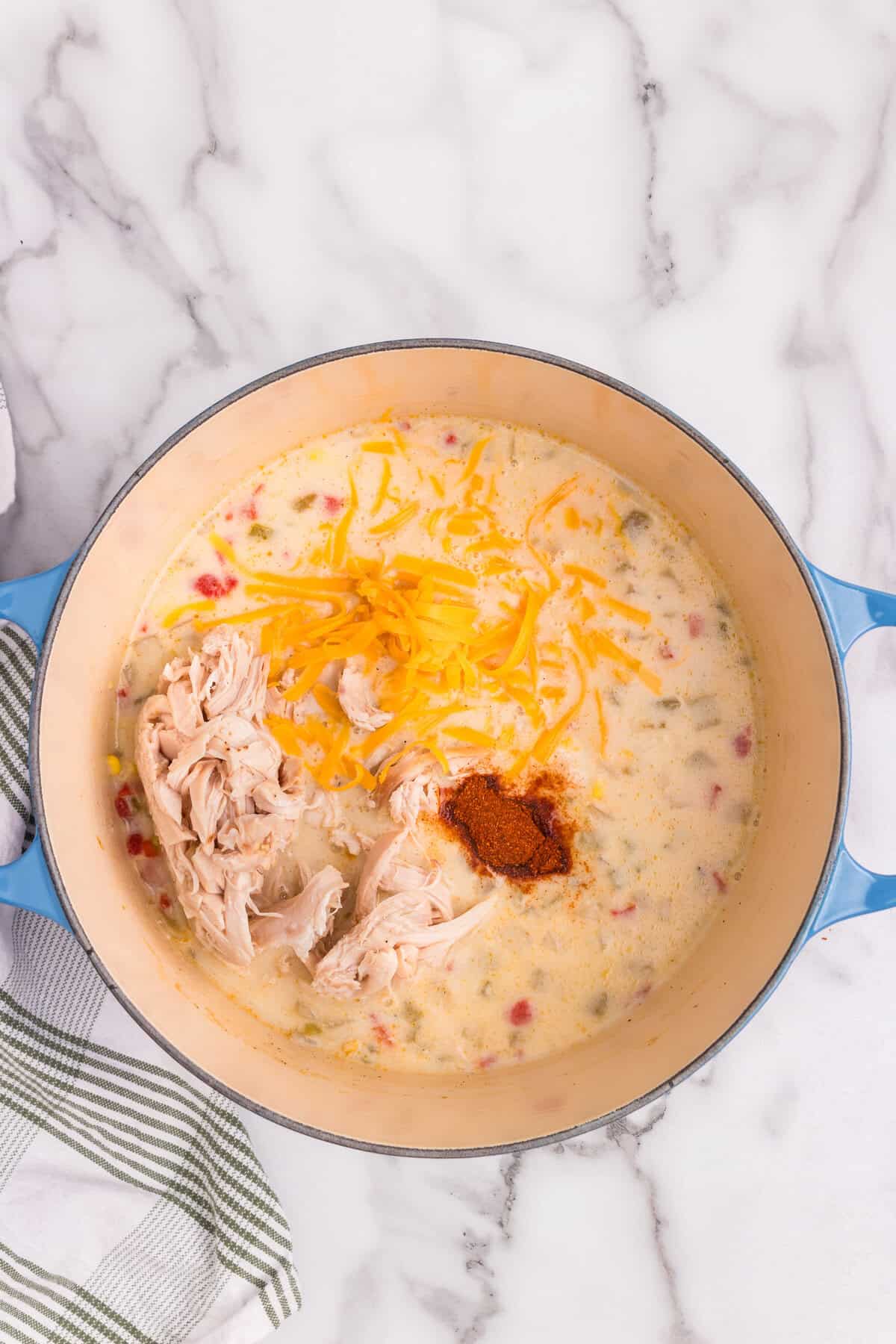 Overhead picture of chicken and corn chowder ingredients in a pot unmixed.