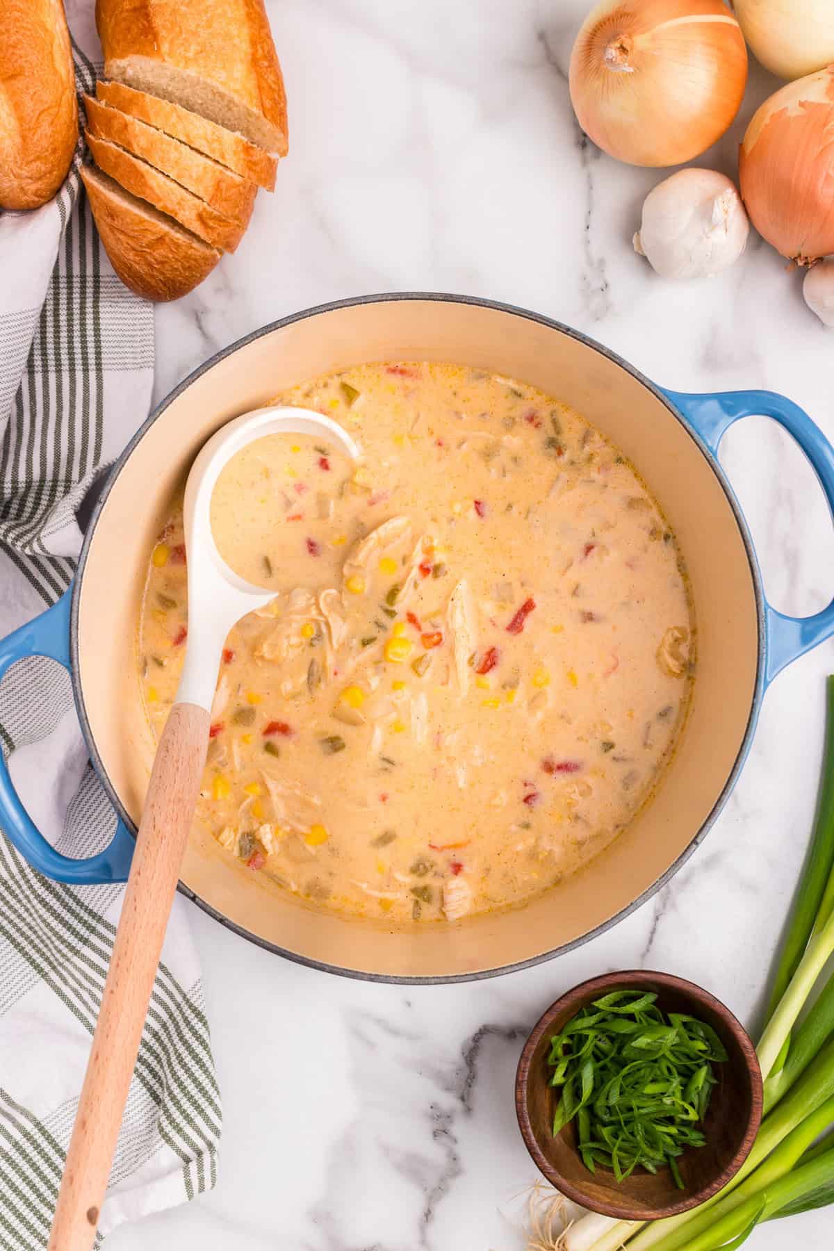 Overhead picture of completed chicken and corn chowder in a pot with a ladle in it.