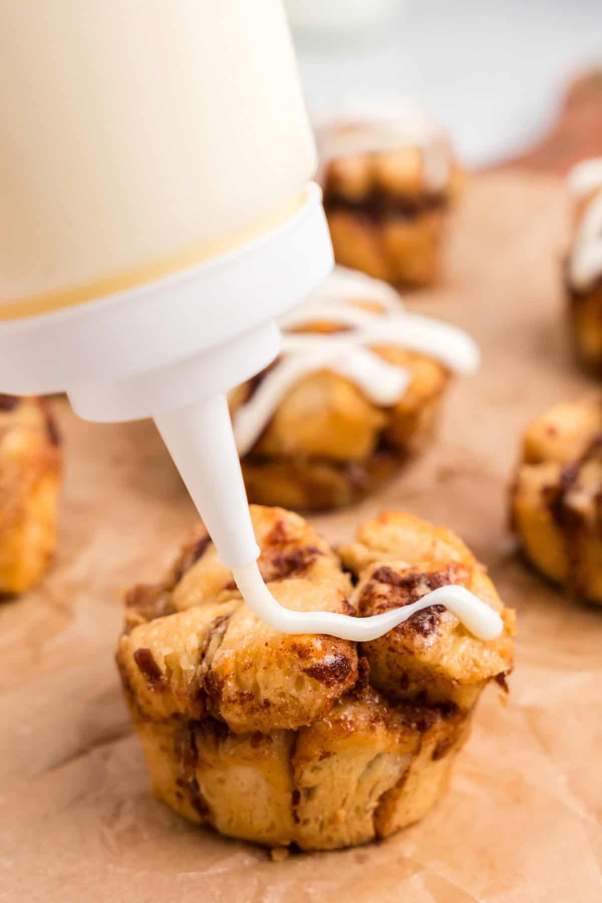 Side picture of cream cheese topping being put on muffins.