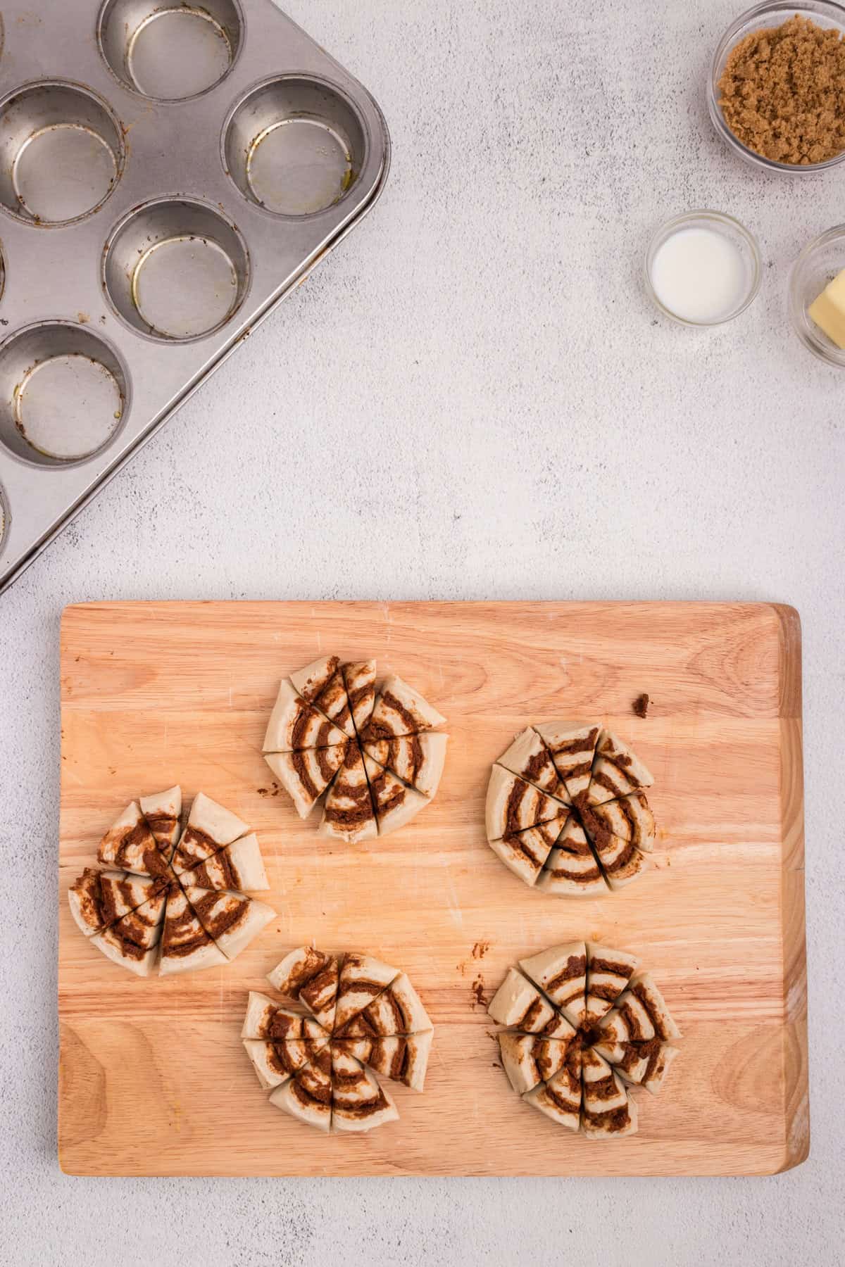 Overhead picture of cut cinnamon rolls on a wooden cutting board.