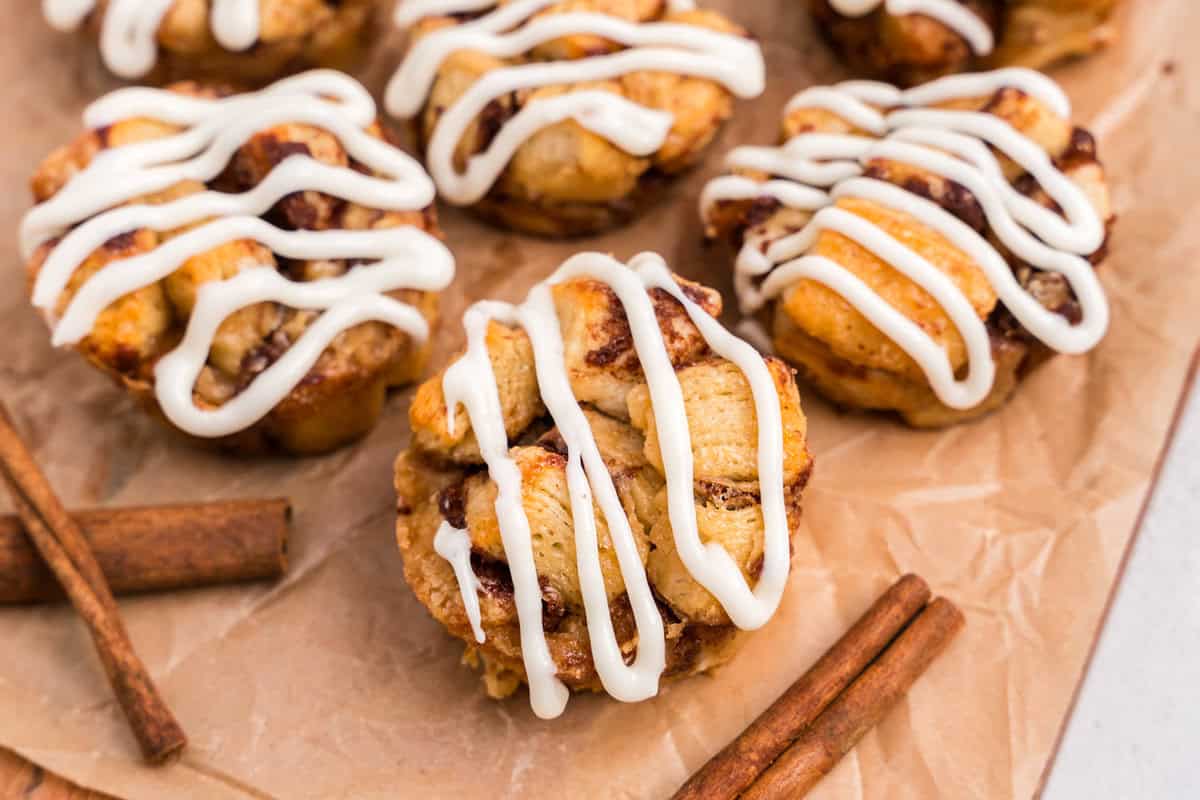 Close up picture of cinnamon roll monkey bread muffins on a wooden cutting board.
