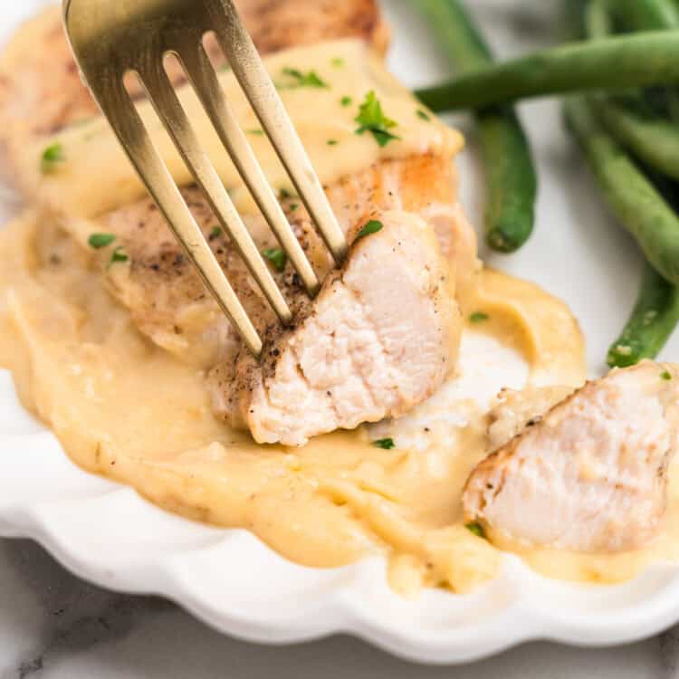 Close up of fork with a piece of Garlic Parmesan Chicken on it.