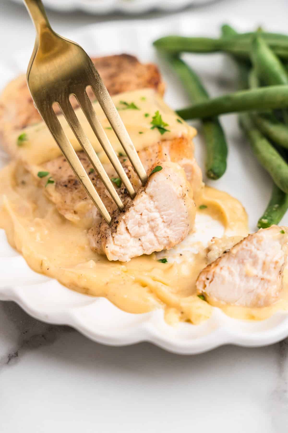 Close up of fork with a piece of Garlic Parmesan Chicken on it.