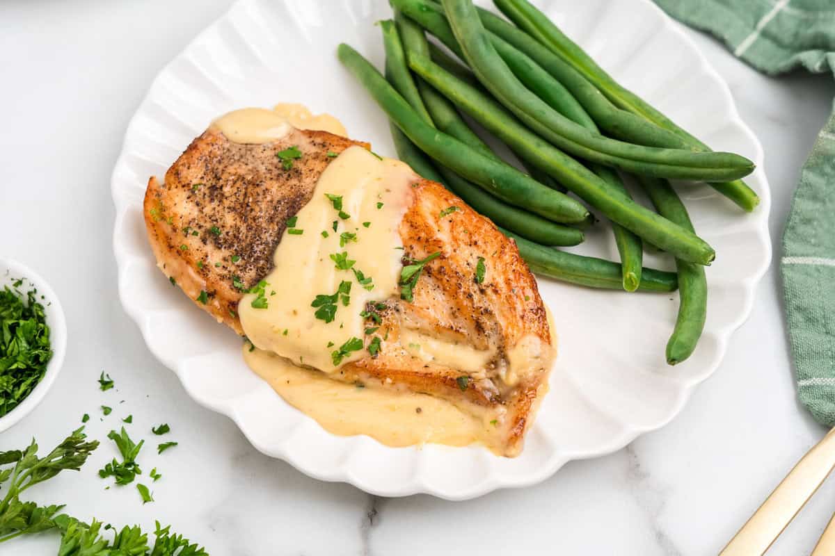 Close up image of completed Garlic Parmesan Chicken on a white plate with green beans.