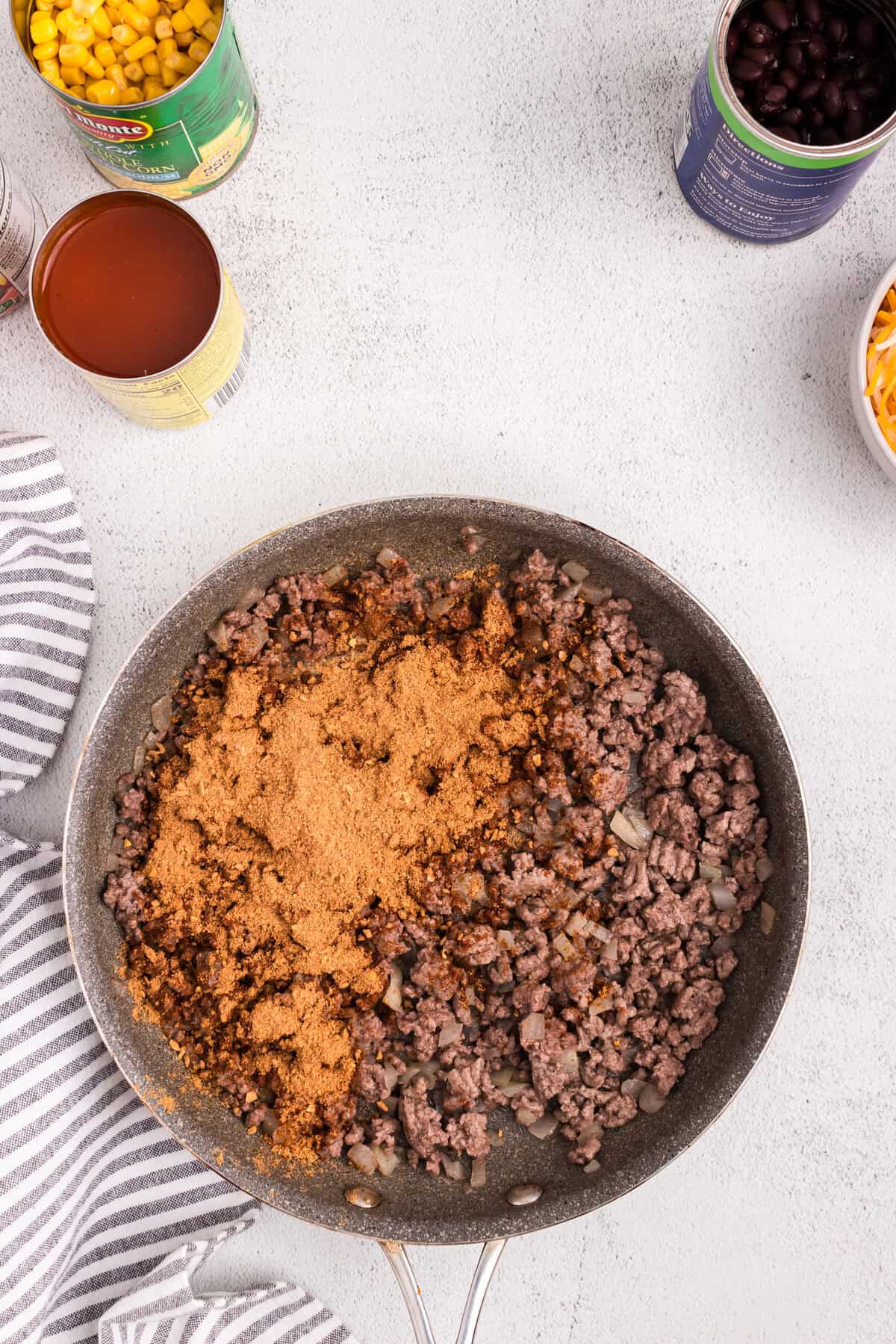 Overhead picture of ground beef and taco seasoning uncombined in a pan.