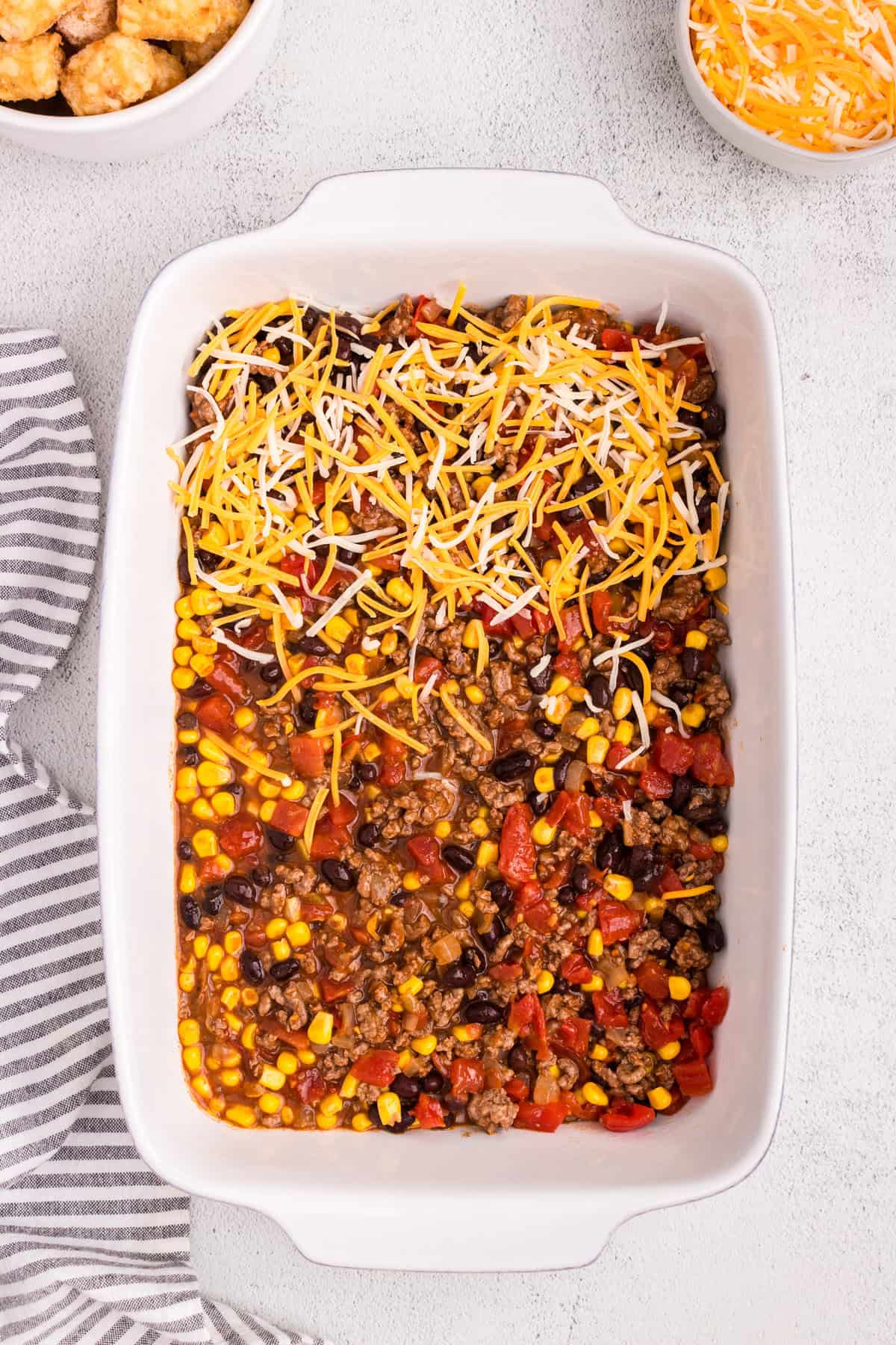 Overhead picture of casserole with cheese sprinkled on half of the pan.