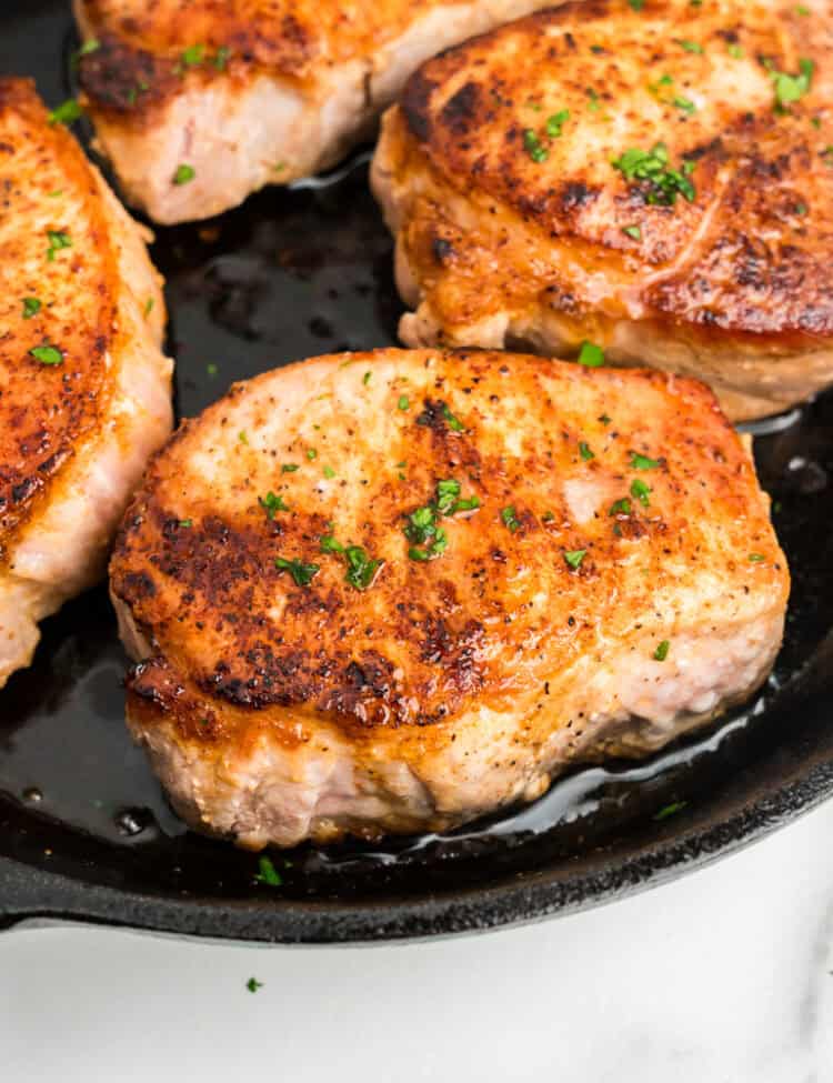 Close up picture of completed Pan Seared Pork Chops in a cast iron skillet.