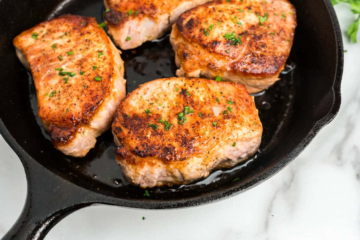 Close up picture of completed Pan Seared Pork Chops in a cast iron skillet.
