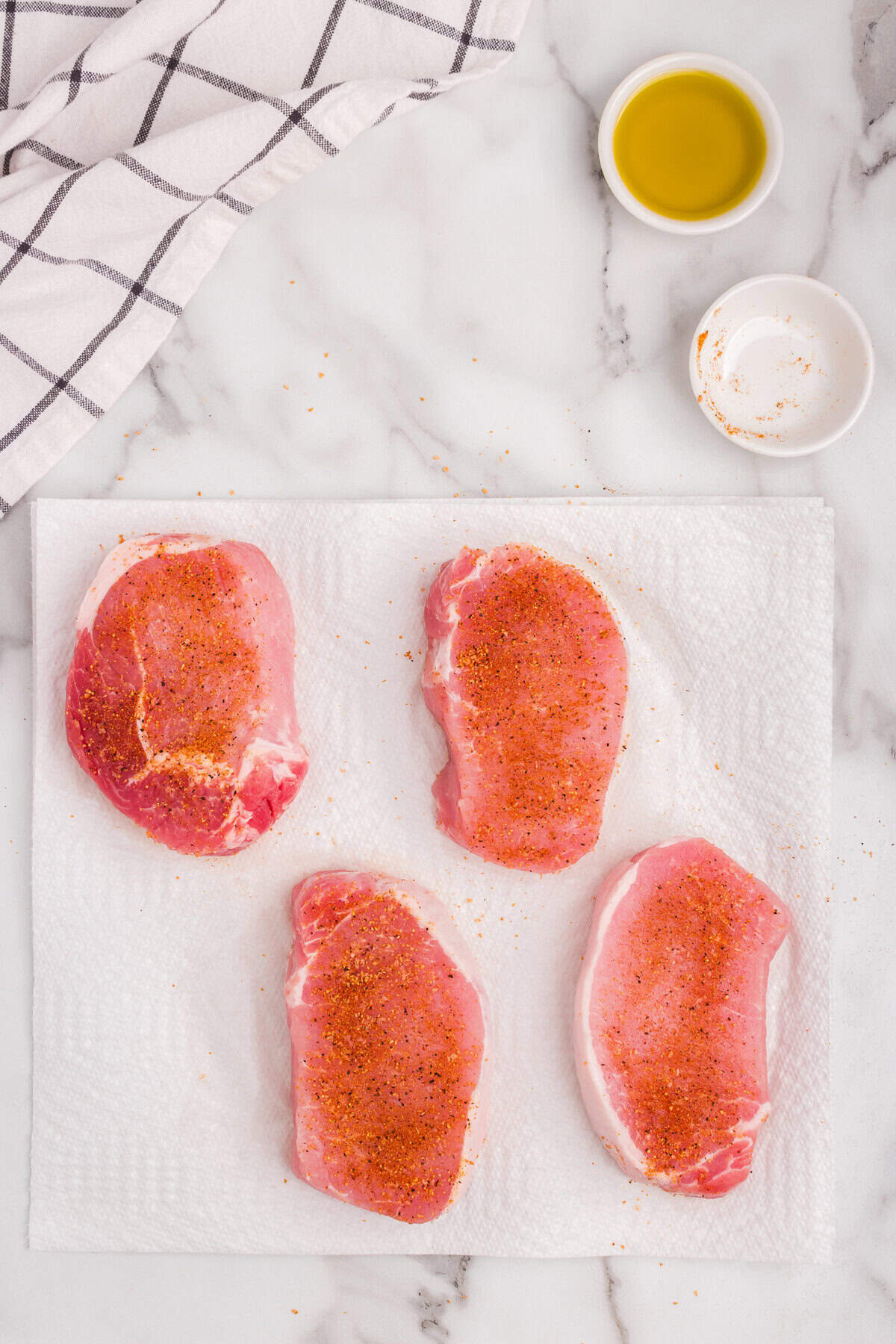 Seasoned porkchops laid on a cutting board.