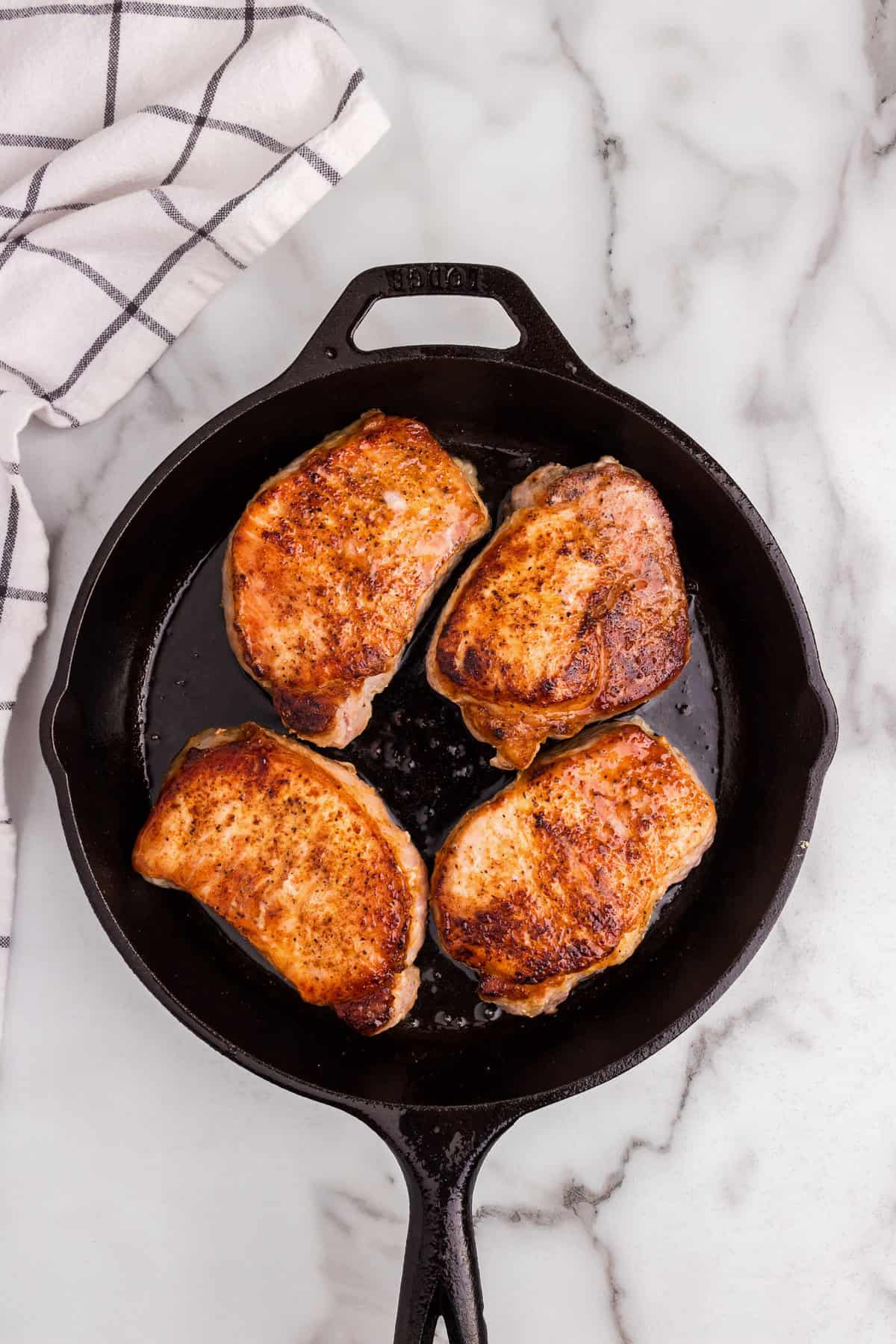 Overhead picture of cooked pork chops in a cast iron skillet.