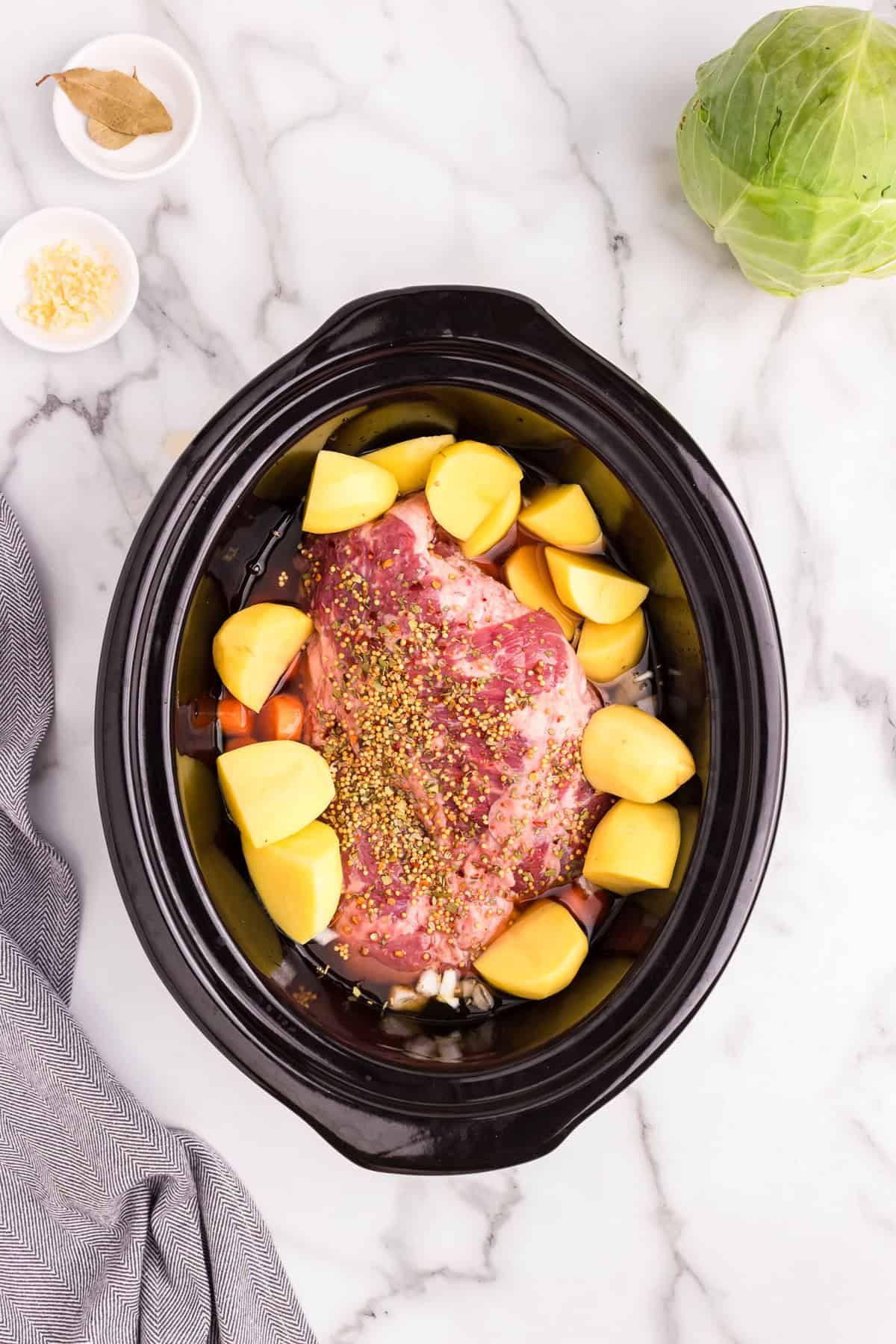 Overhead picture of raw corned beef and cabbage ingredients in the crock pot.