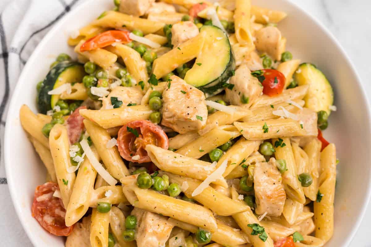 Close up picture of chicken primavera on a white plate.