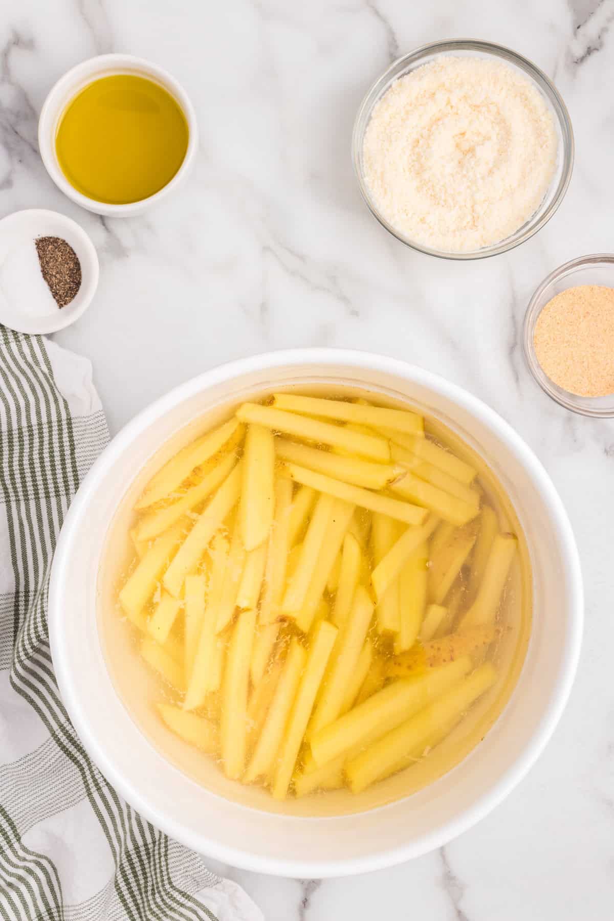 Overhead picture of cut potatoes soaking in water.