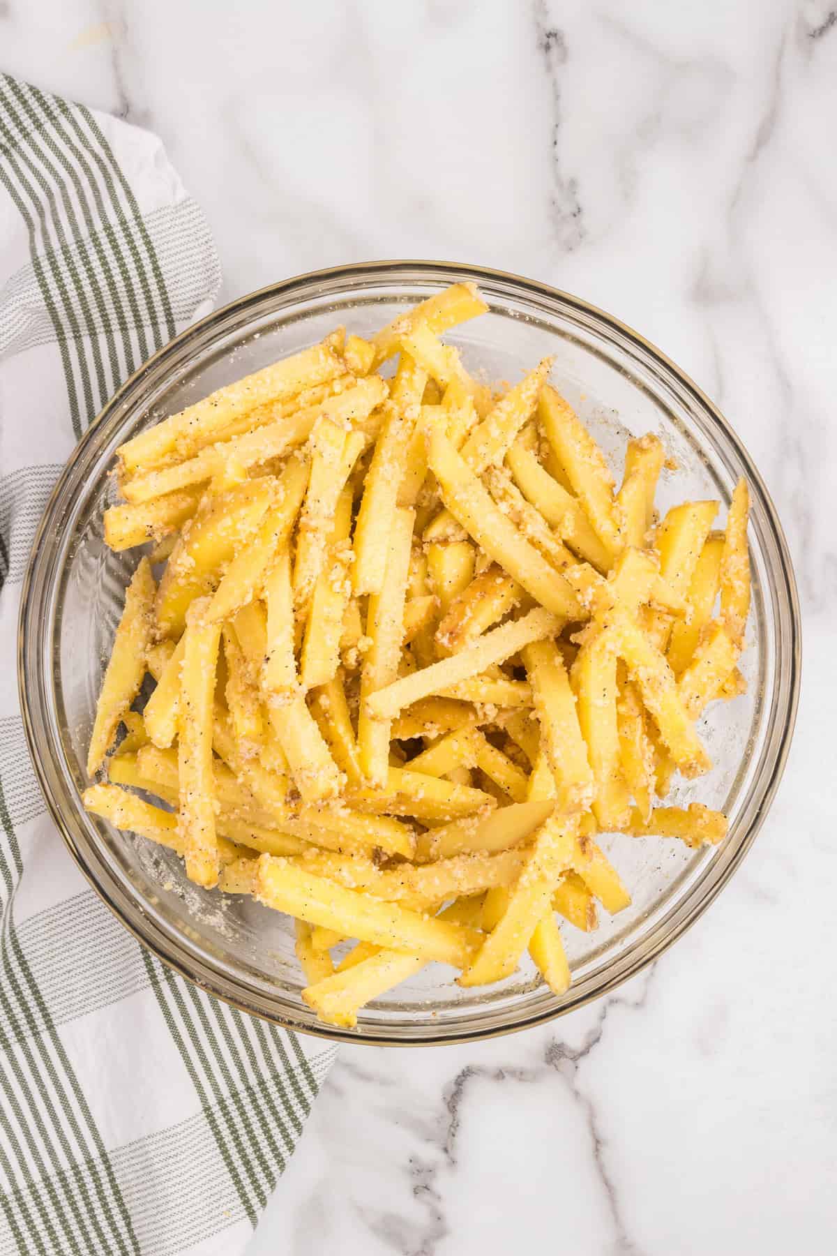 Overhead picture of garlic parmesan fries ingredients combined in a bowl.