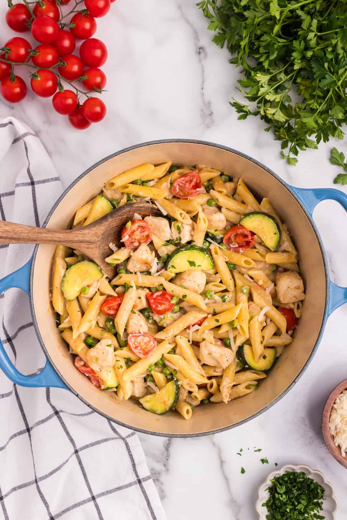 Overhead picture of chicken primavera in a pot with a wooden spoon.