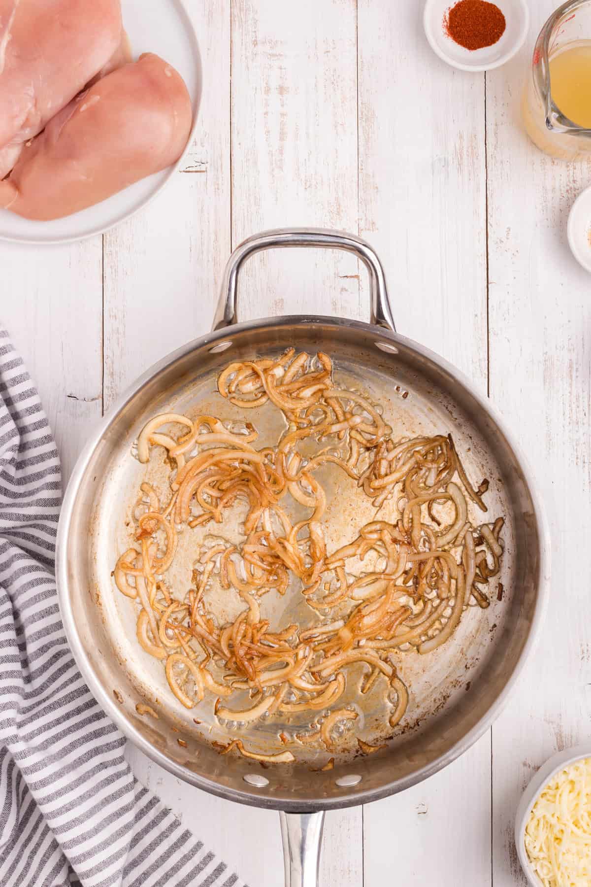 Overhead picture of onions sauted in a metal pan.